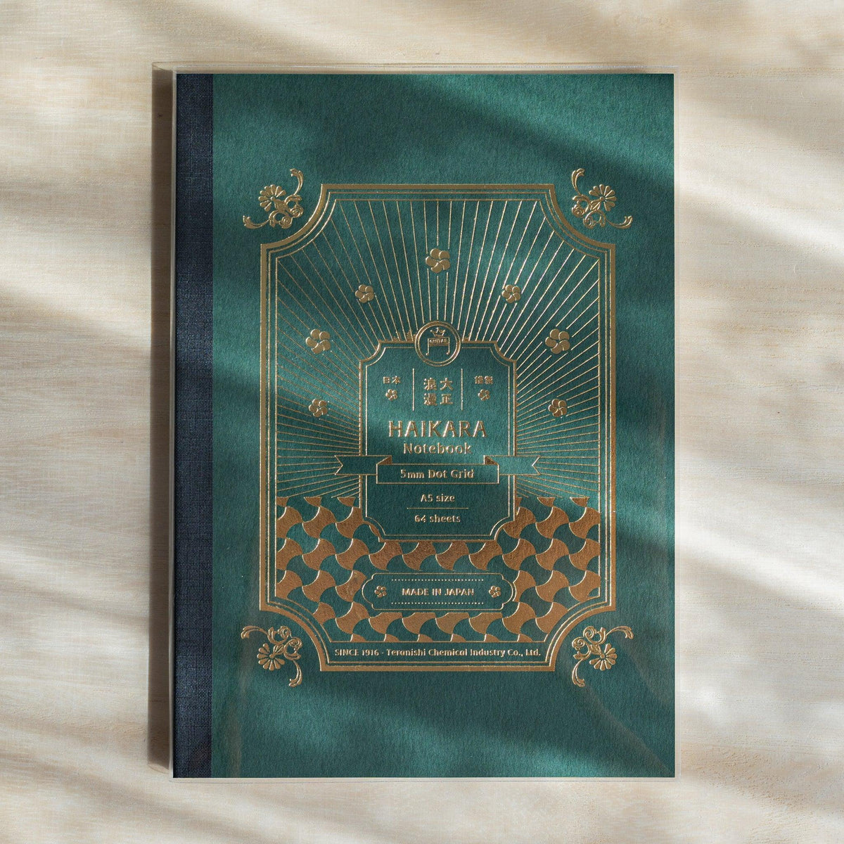 Dark green HAIKARA notebook cover with gold foil arch frame, flower motifs and interlocking wave pattern, cloth spine