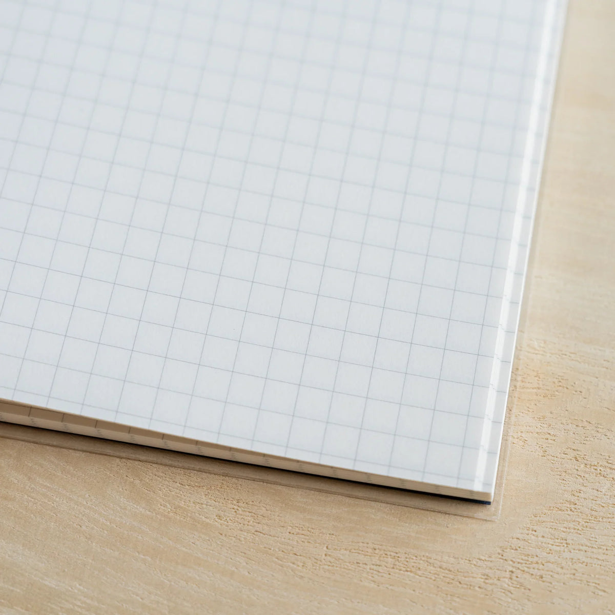 Close-up of the corner of a 5mm grid page showing grey ruling, paper texture and the stacked edge of the block