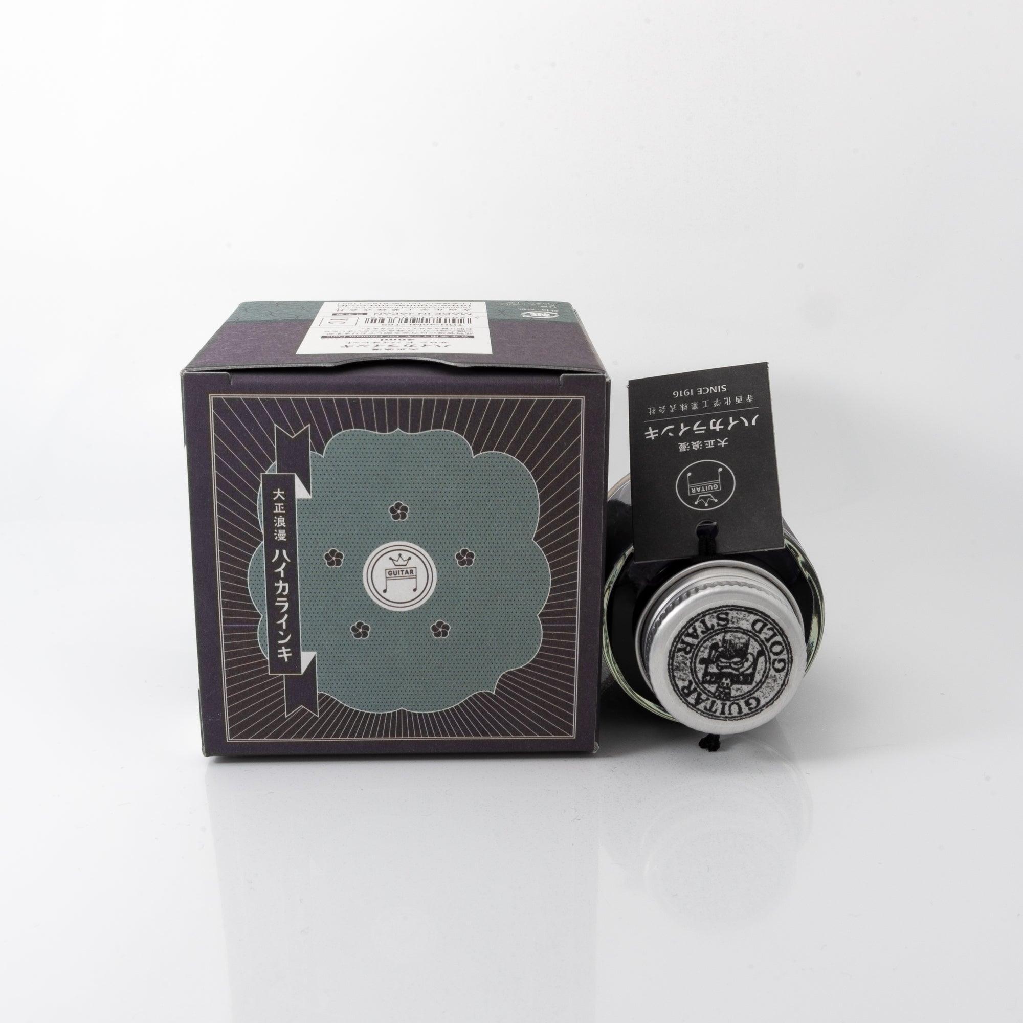 Taisho Romance Salon de Violet fountain pen ink bottle and matching pen, arranged on a wooden desk, emphasizing coordinated design.