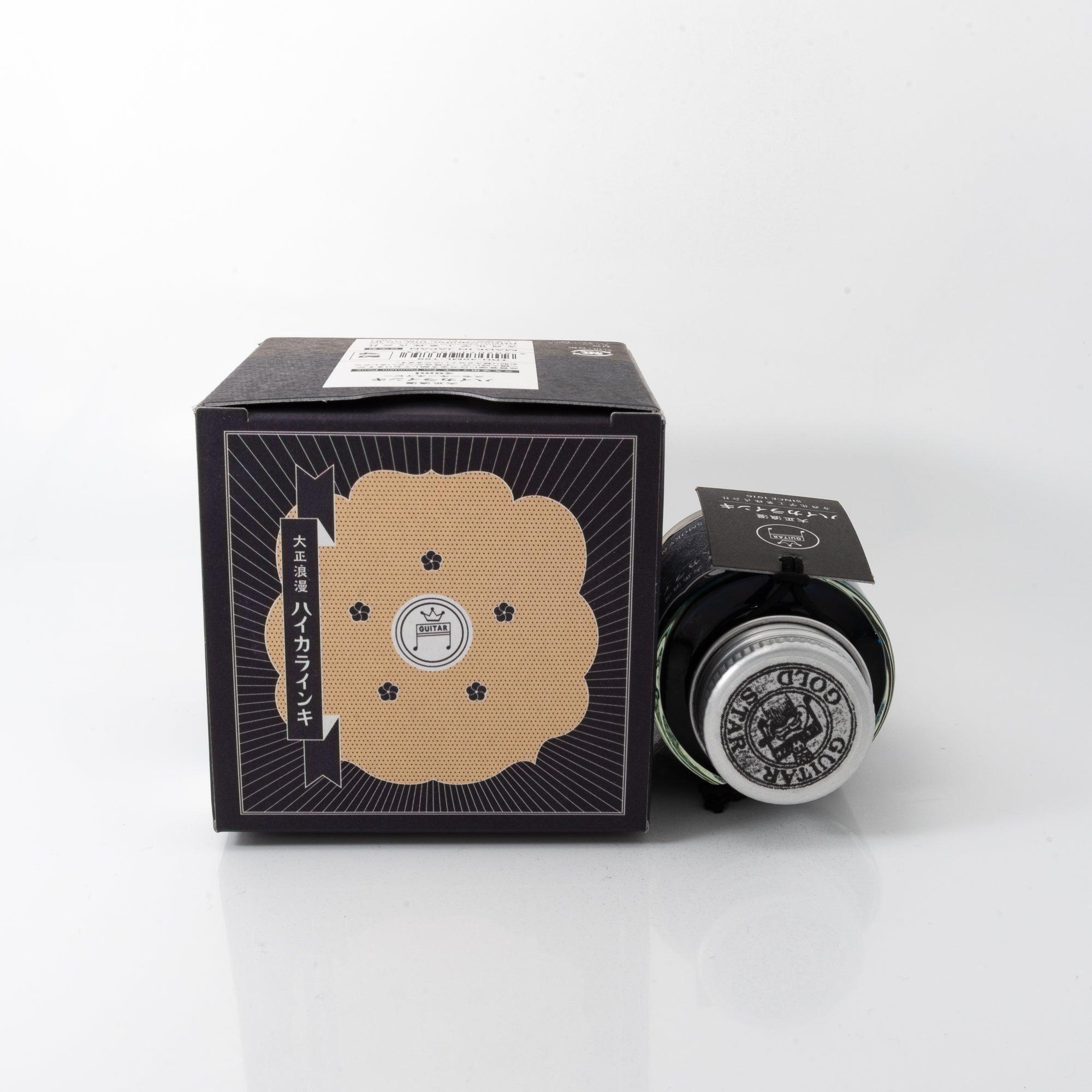 Taisho Romance Smoky Navy fountain pen ink bottle and matching pen, arranged on a wooden desk, emphasizing elegant design.