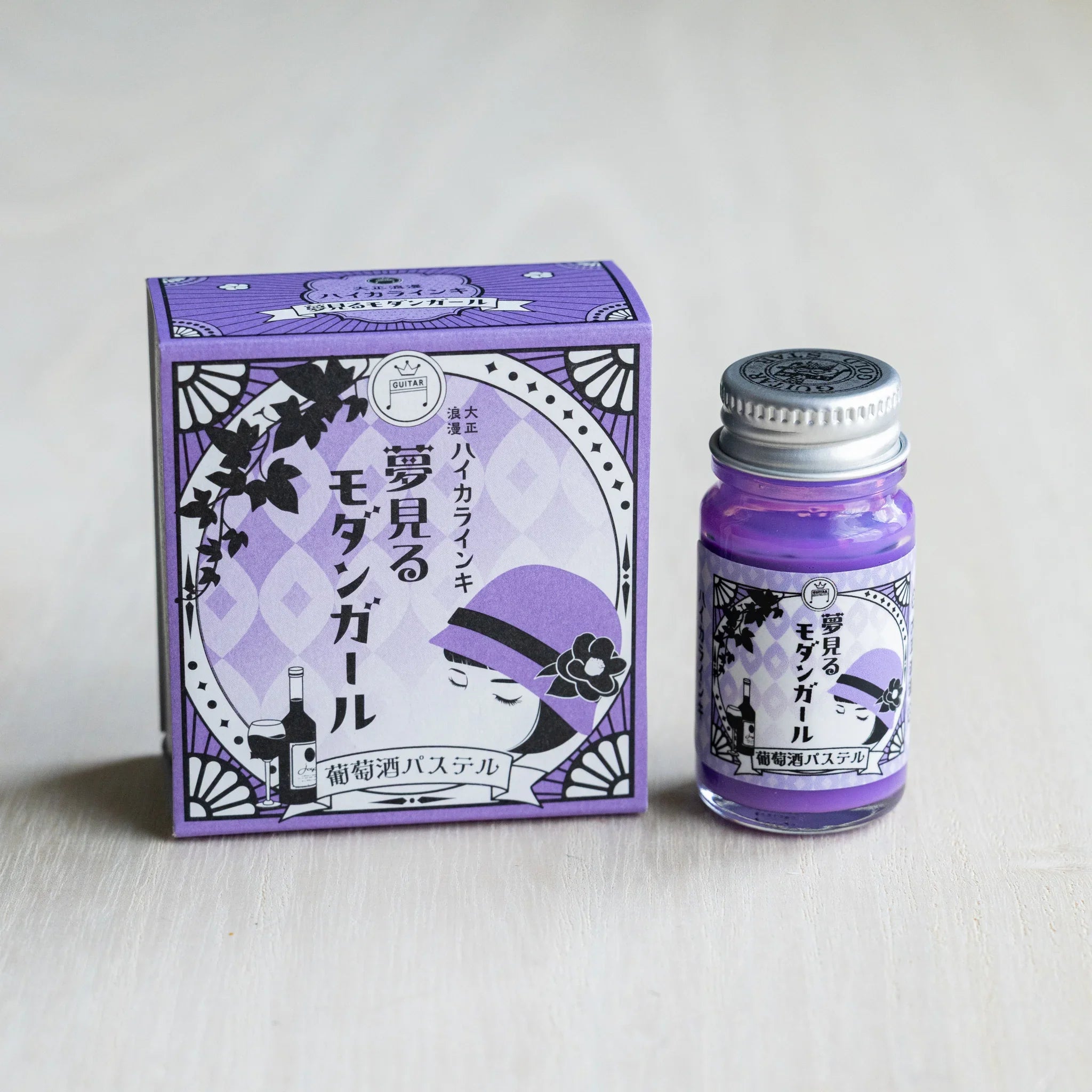 Taisho Romance Wine Pastel ink box in lavender beside a 12 ml glass bottle of opaque purple pigment ink