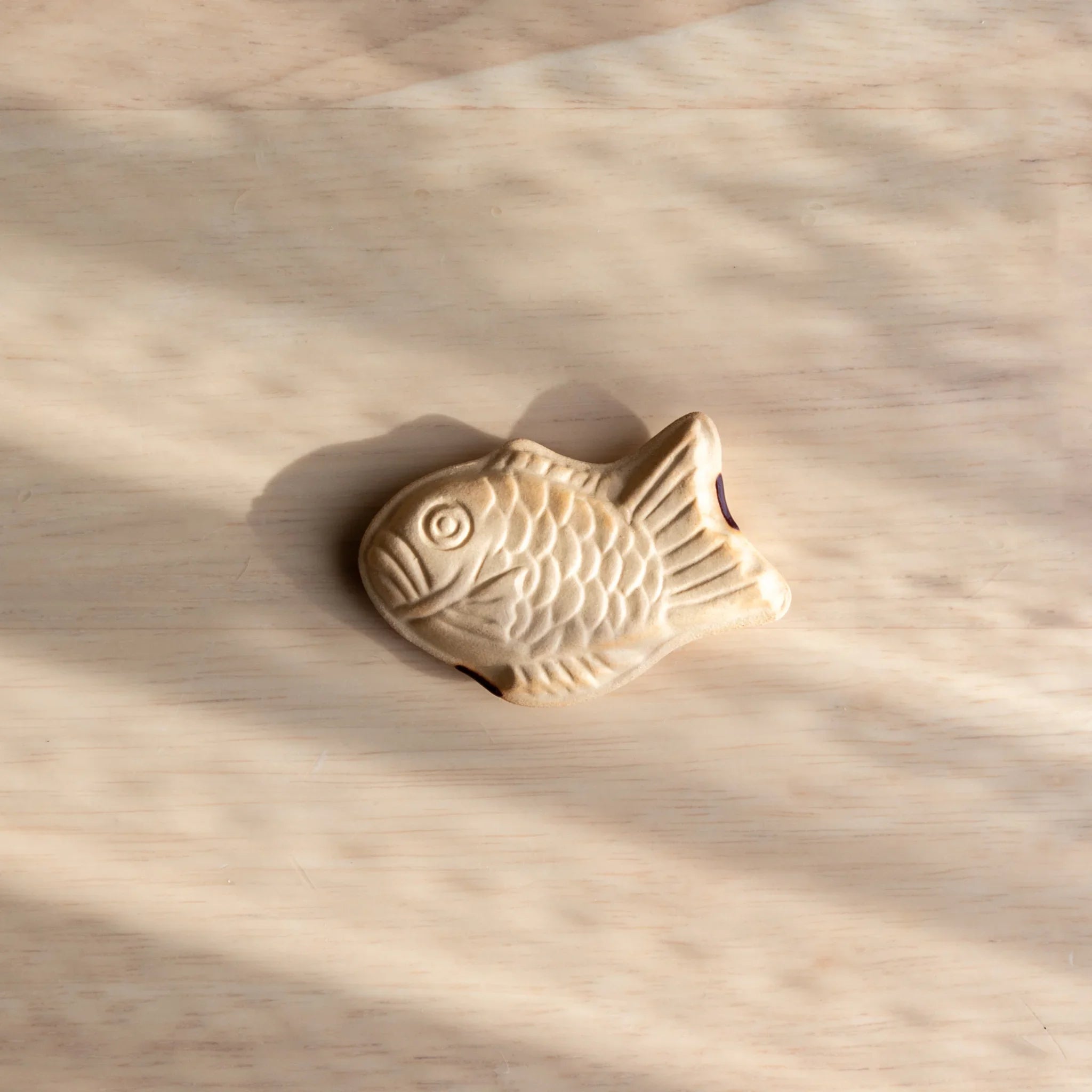 Taiyaki Handcrafted Pen Rest shaped like traditional Japanese fish cake with golden ceramic finish and surface texture