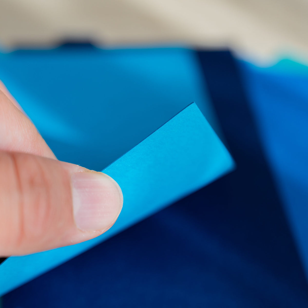 Fingertip lifting the corner of a sky blue Mermaid divider over navy and blue sheets