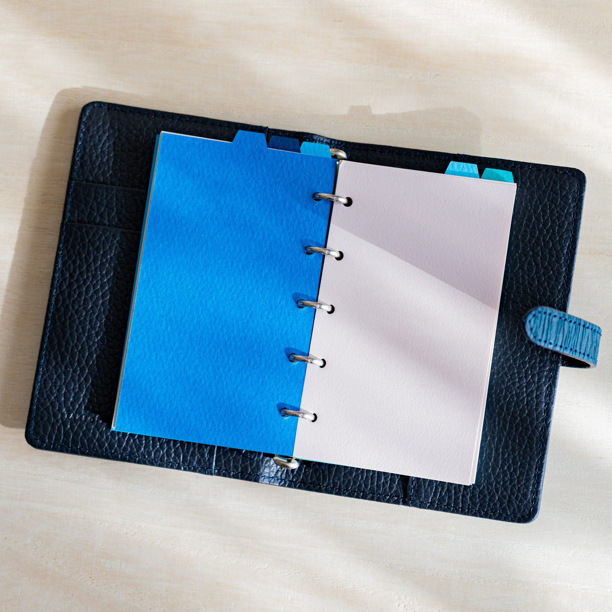 Open navy planner with a cobalt Mermaid M5 divider beside a pale pink page