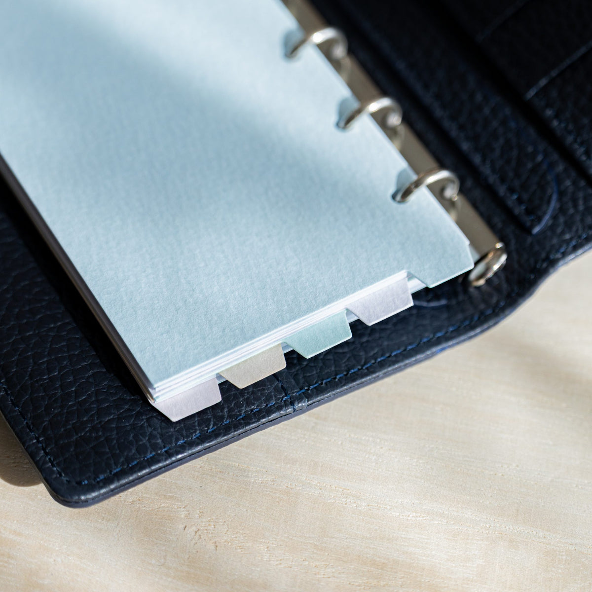Mermaid M5 dividers in a navy planner showing staggered pastel top tabs along the page edge