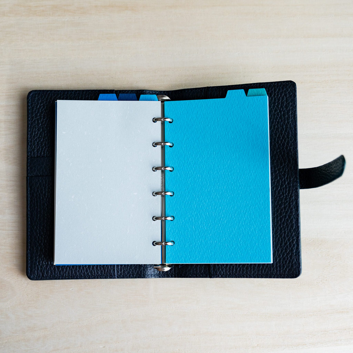Open navy planner with a white page and a sky blue Mermaid Mini 6 divider, blue tabs on top