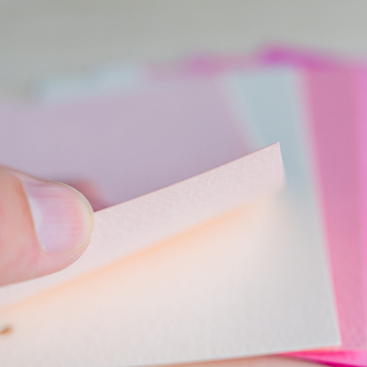 Fingertip lifting the corner of a coral Mermaid Mini 6 divider over bright pink sheets