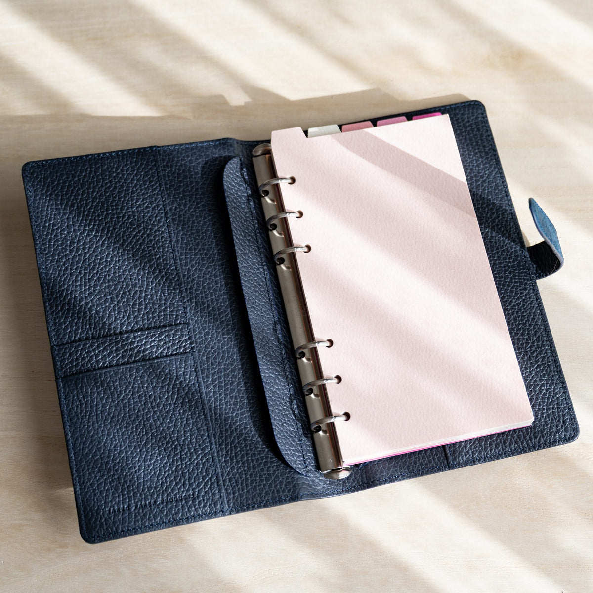 Mermaid Assorted Pinks divider on the rings of an open Ise Gikakushi Bible planner with navy leather interior