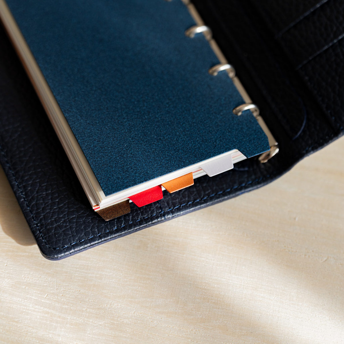 Stardream M5 dividers in a navy planner with staggered copper, ruby and opal tabs along the edge
