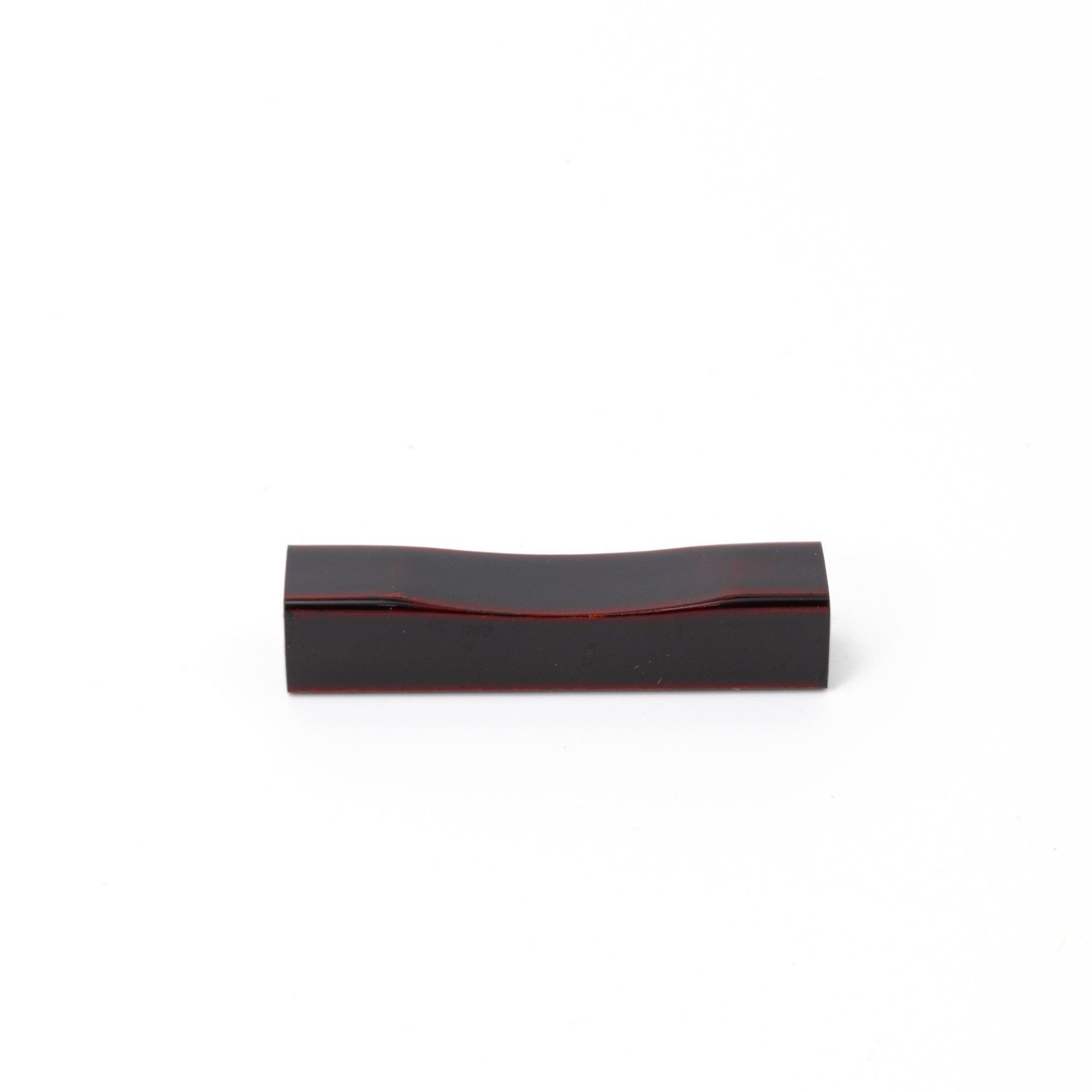 A straight-on view of a red Japanese stationery pen rest, showcasing its smooth, minimalistic design.