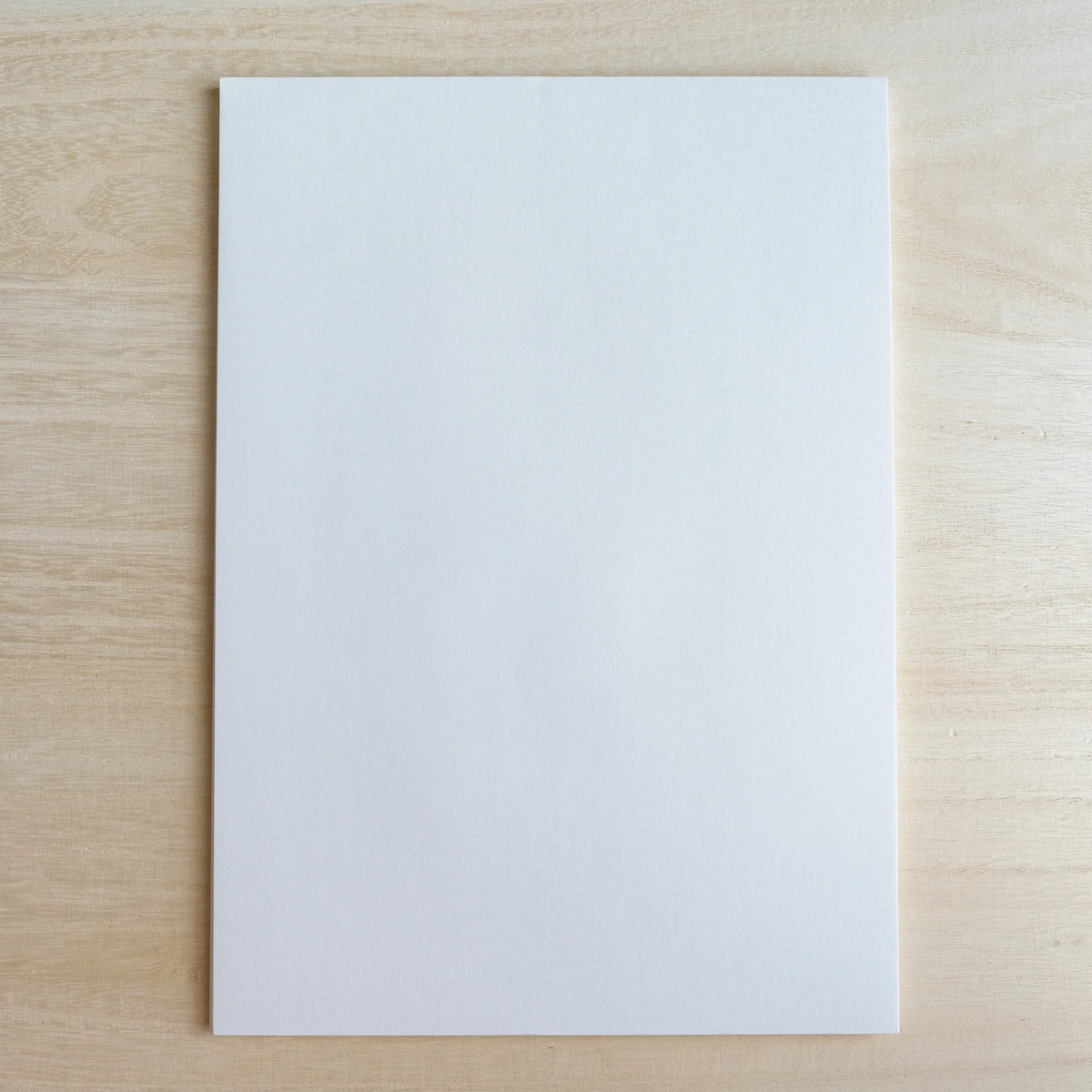 Single blank sheet of Tateyama A4 paper in bright white on a pale wood surface