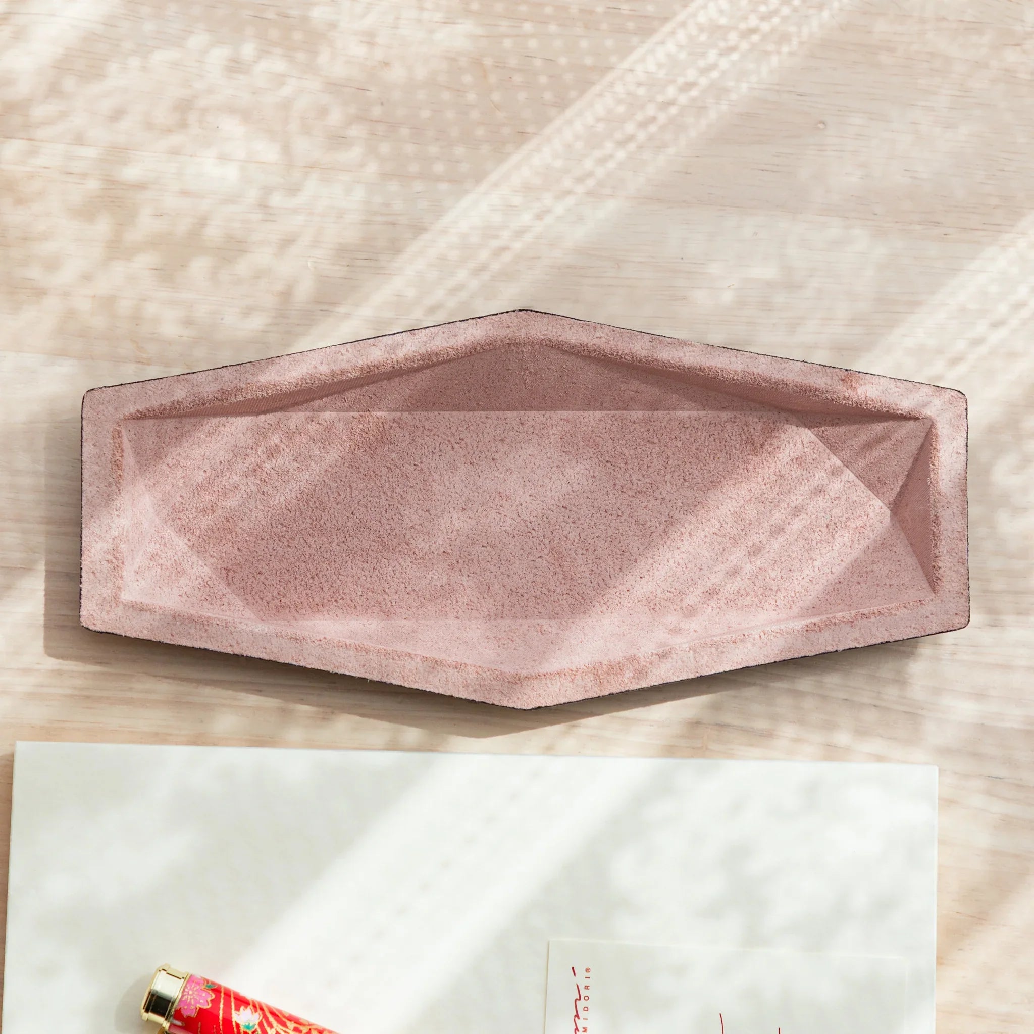 Pink suede hexagonal slim pen tray shown empty from above, revealing geometric angled interior walls and suede texture