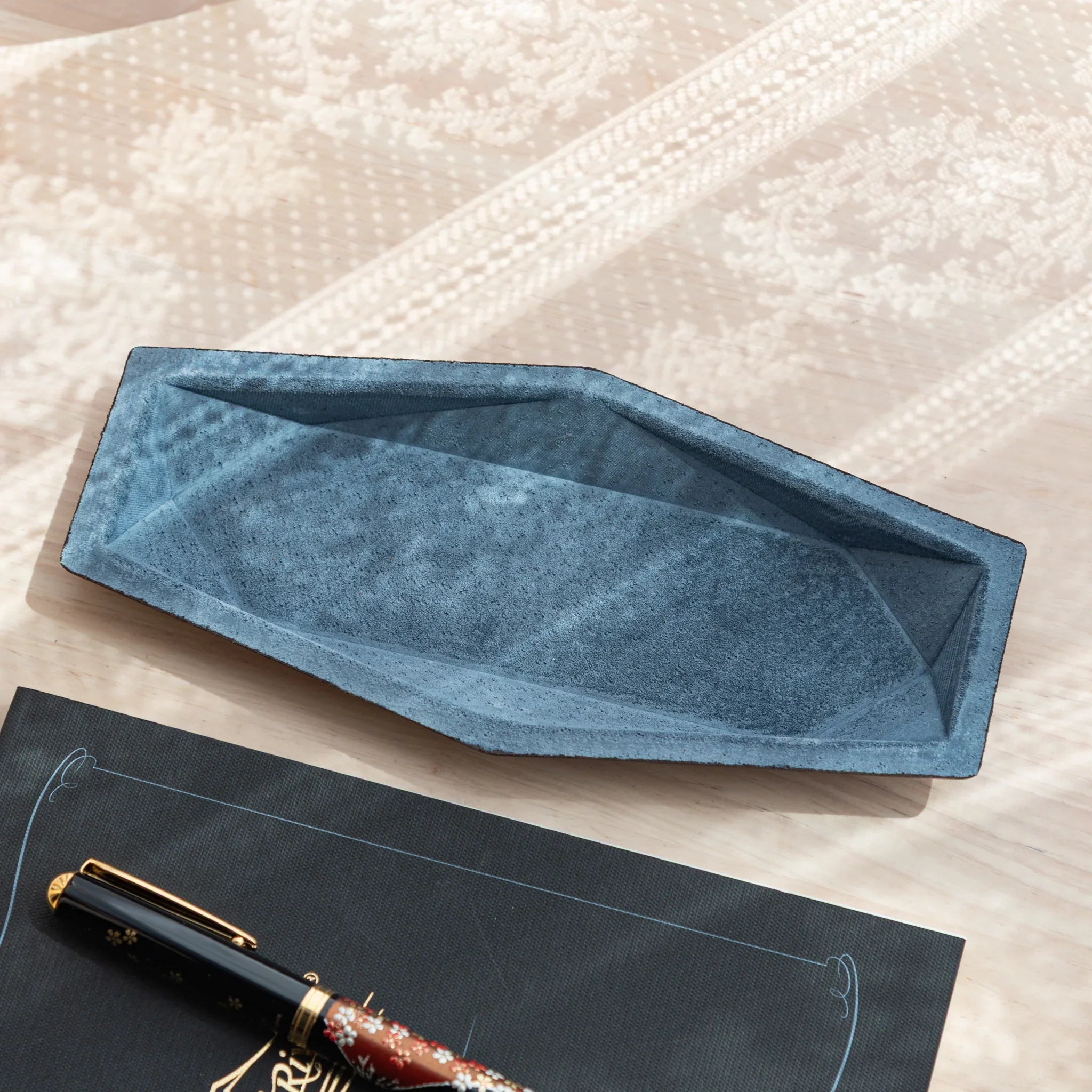 Geometric navy Japanese Pen Tray made of Tatsuno leather and suede, displayed under natural window light.