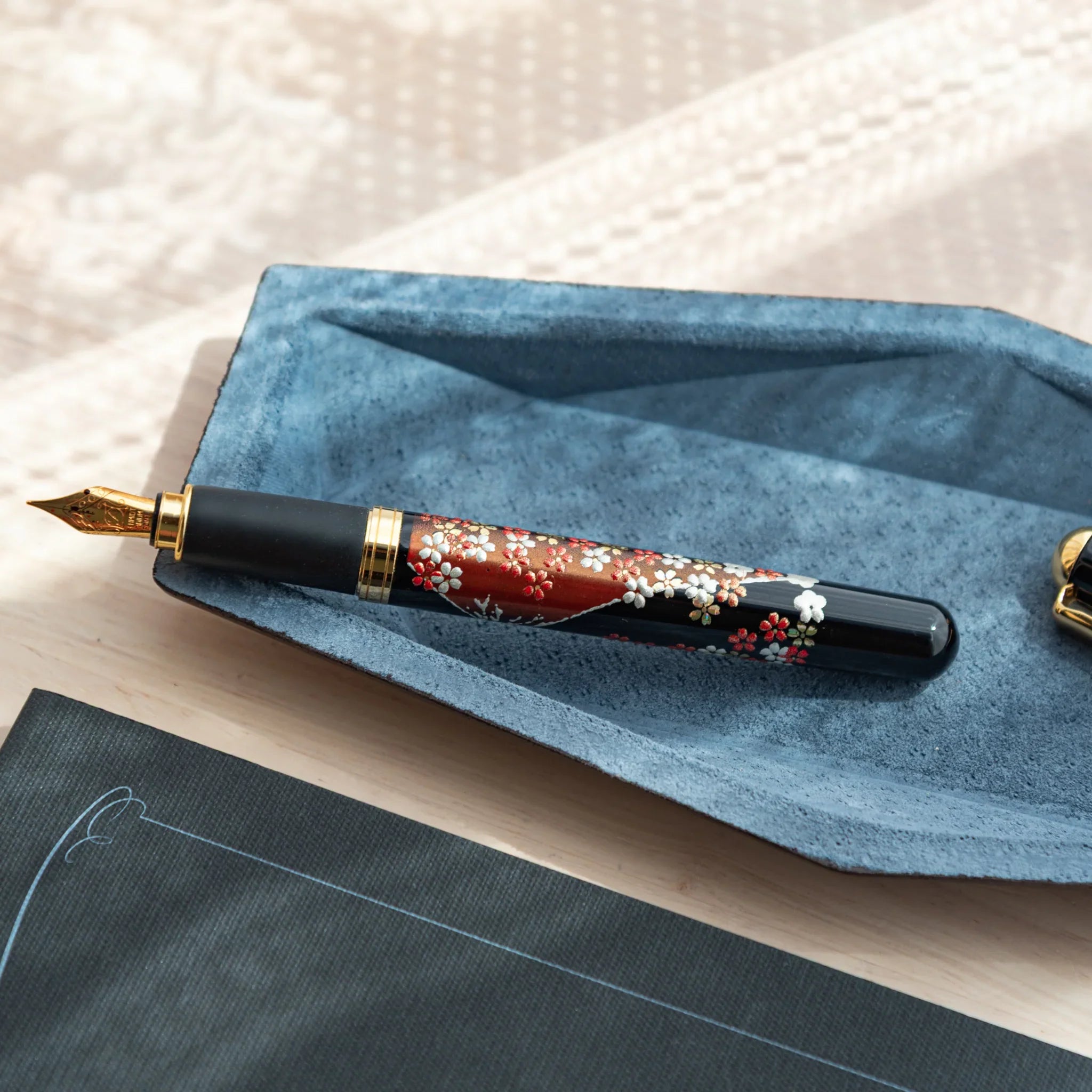 Close-up of Japanese Fountain Pen with floral lacquer design on a soft suede-lined leather tray.