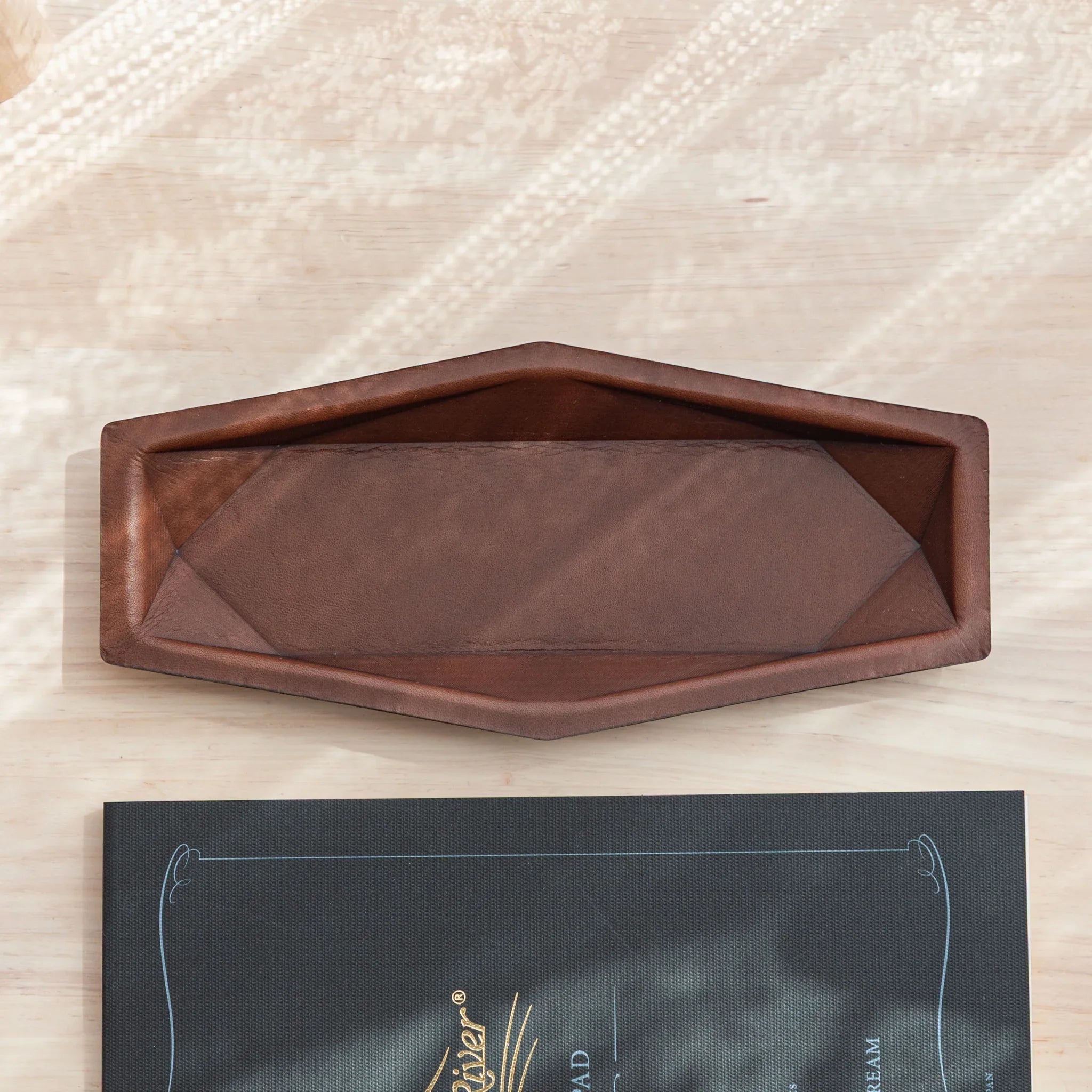 Angled view showcasing the empty interior brown suede lining and distinct hexagonal structure of cognac-toned leather tray