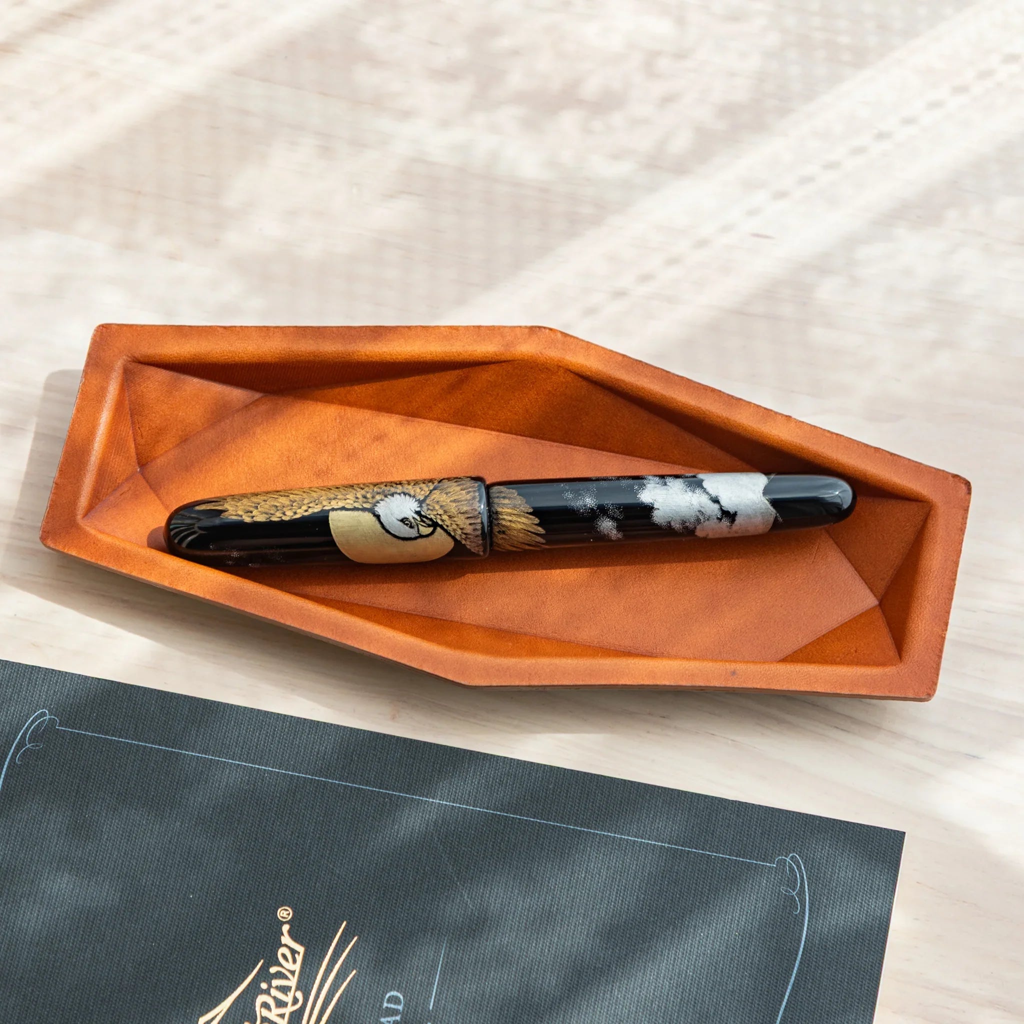 Side-angled view emphasizing the slim structural construction and rounded protective leather edges of pen storage tray