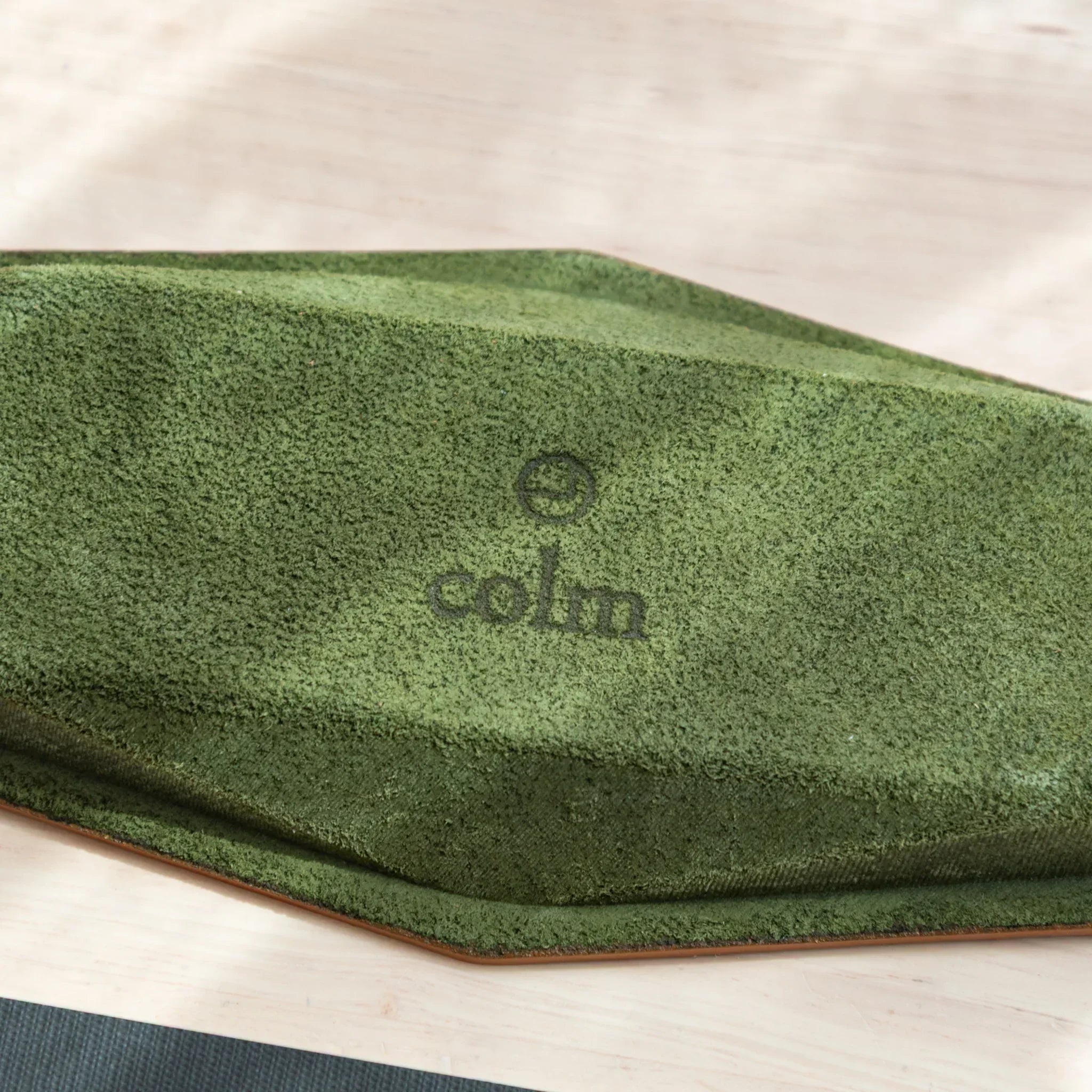 Close-up of colm logo on green suede underside of Japanese Pen Tray.