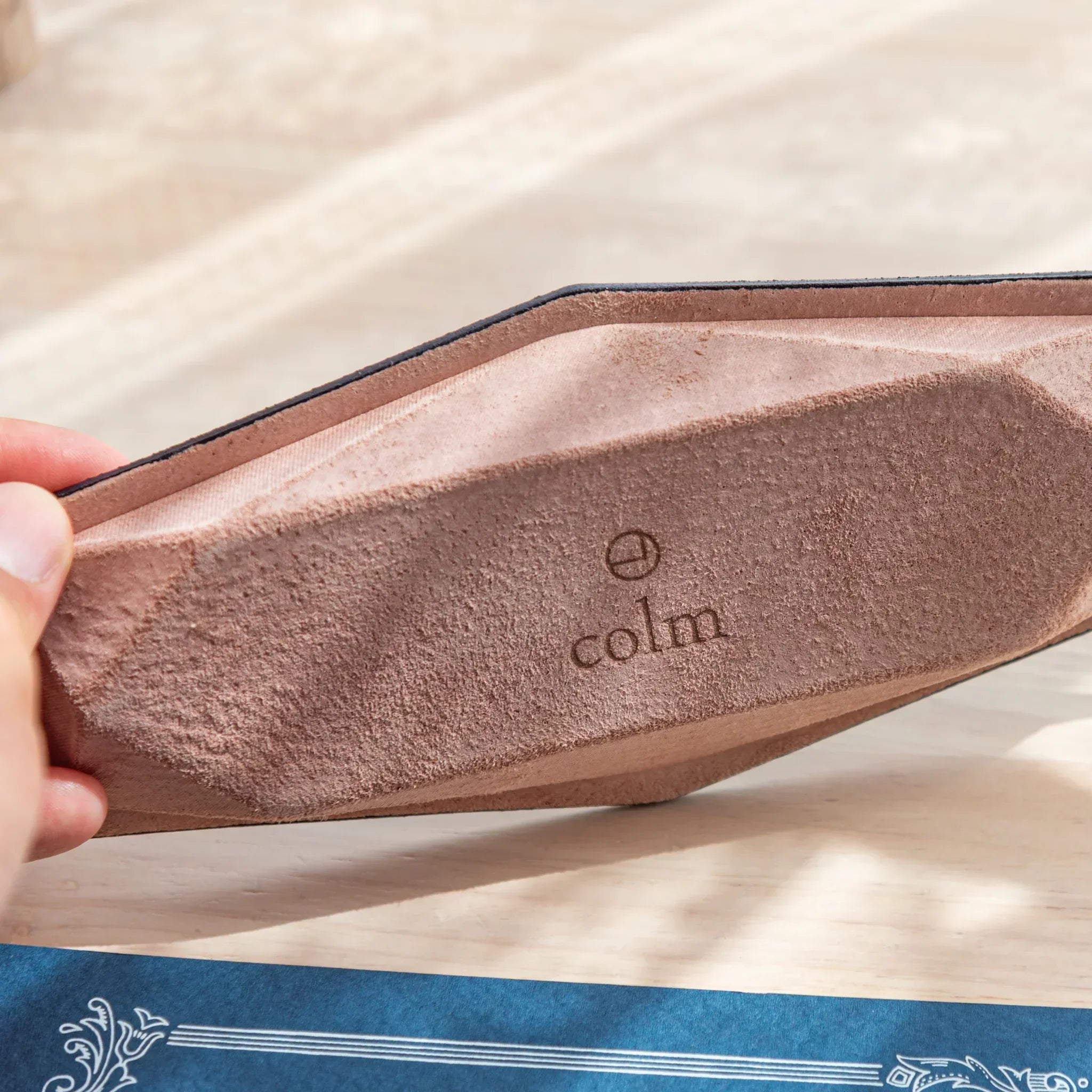 Underside of Japanese Pen Tray made of natural leather, embossed with "colm" logo.