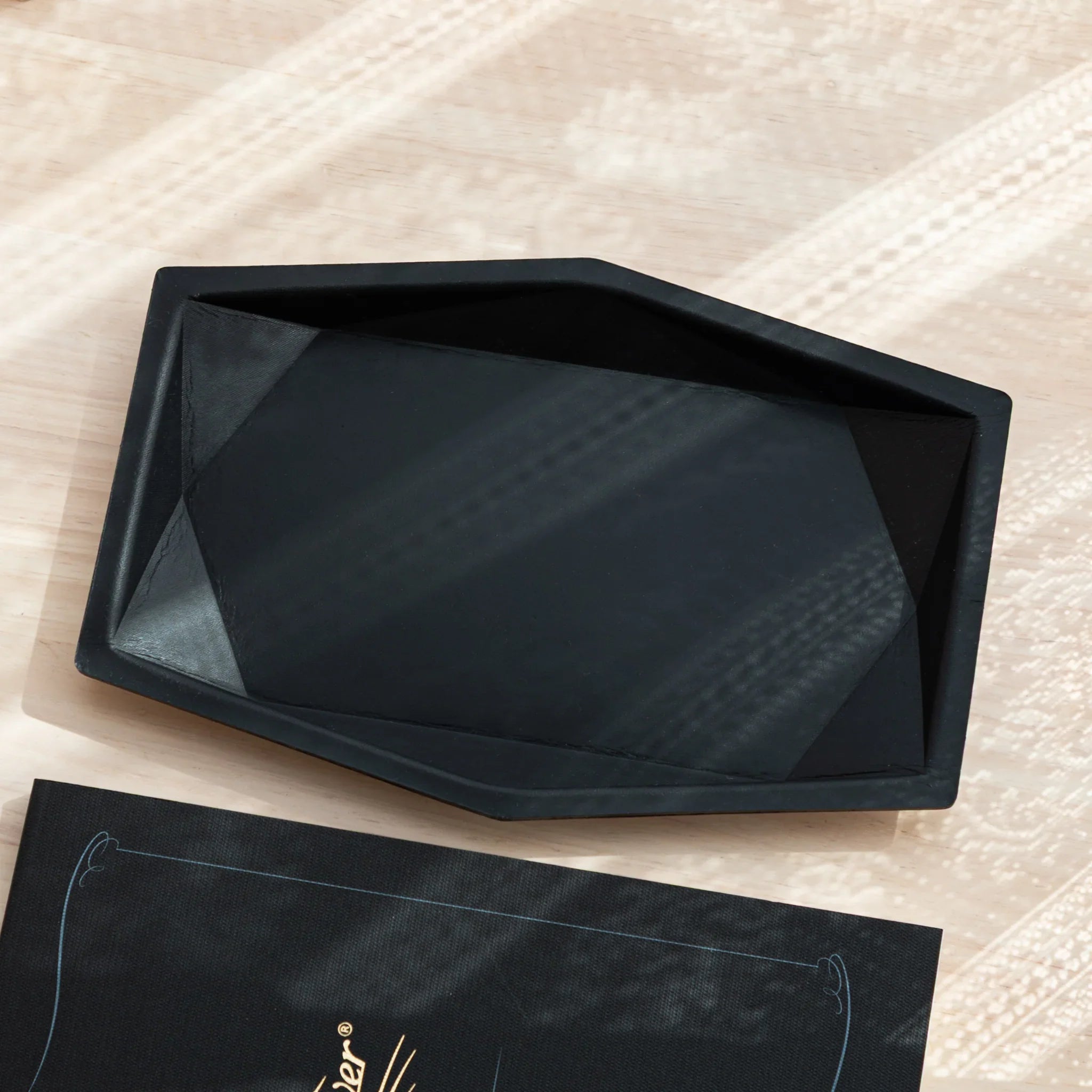 Black hexagonal leather pen tray at angled view, empty interior showing distinctive hexagonal shape and design clearly