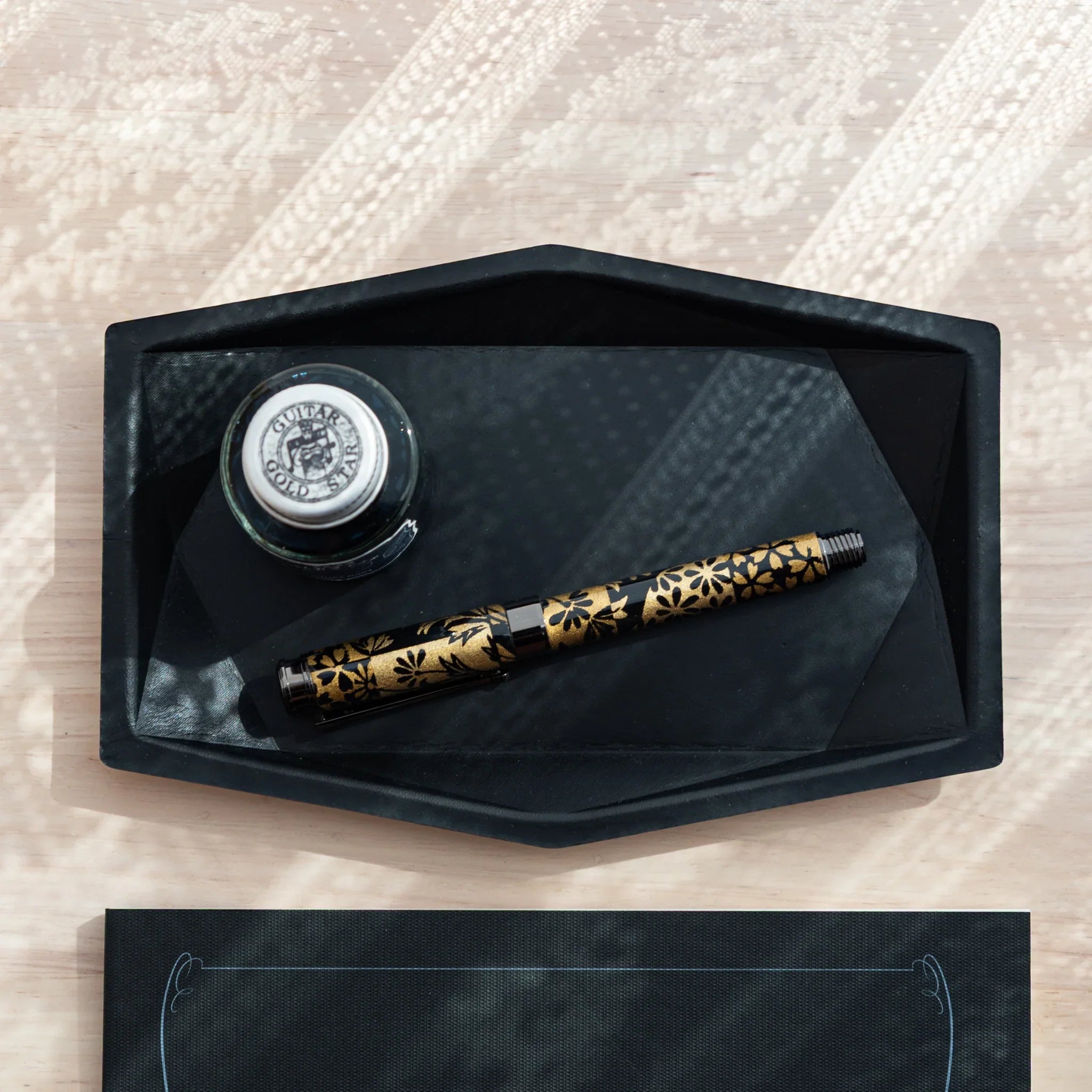 Black Japanese Pen Tray holding ink bottle and Japanese Fountain Pen with gold floral motif.