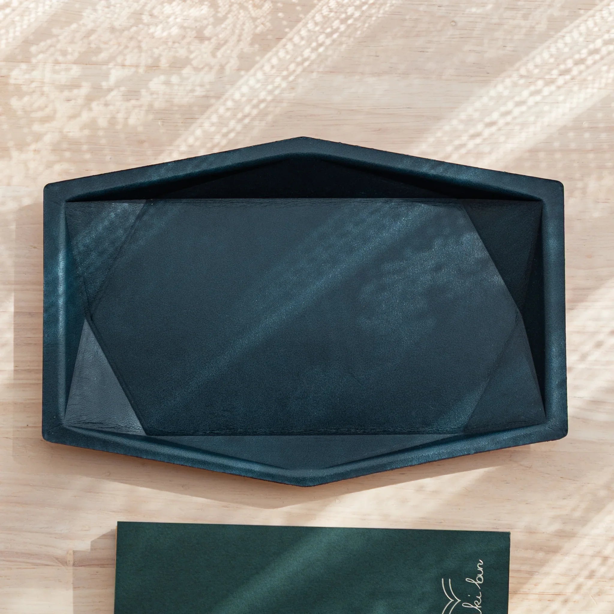 Hexagonal leather pen tray rear view with suede backing material and embossed identification logo marking visible