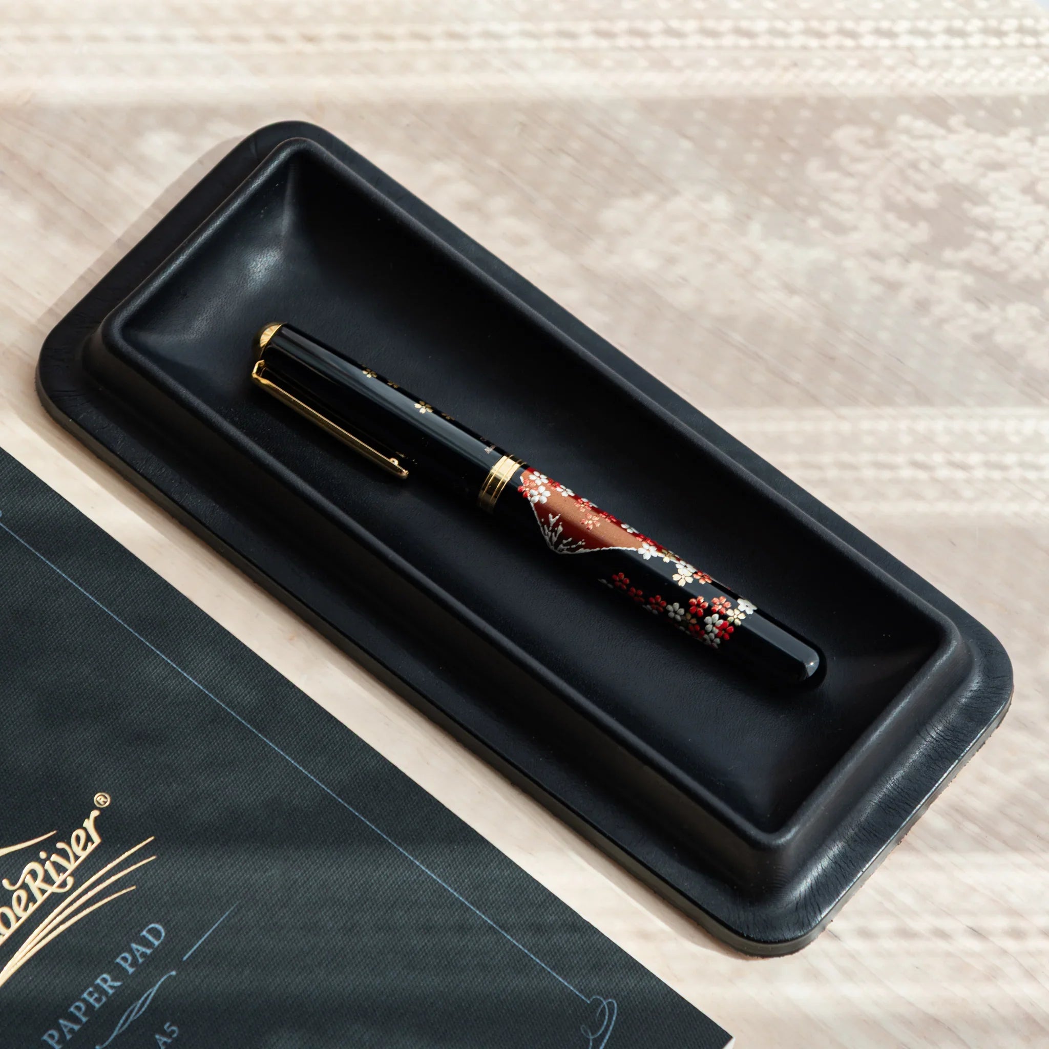 Black Tatsuno Leather Pen Tray holding Japanese Fountain Pen with floral design.