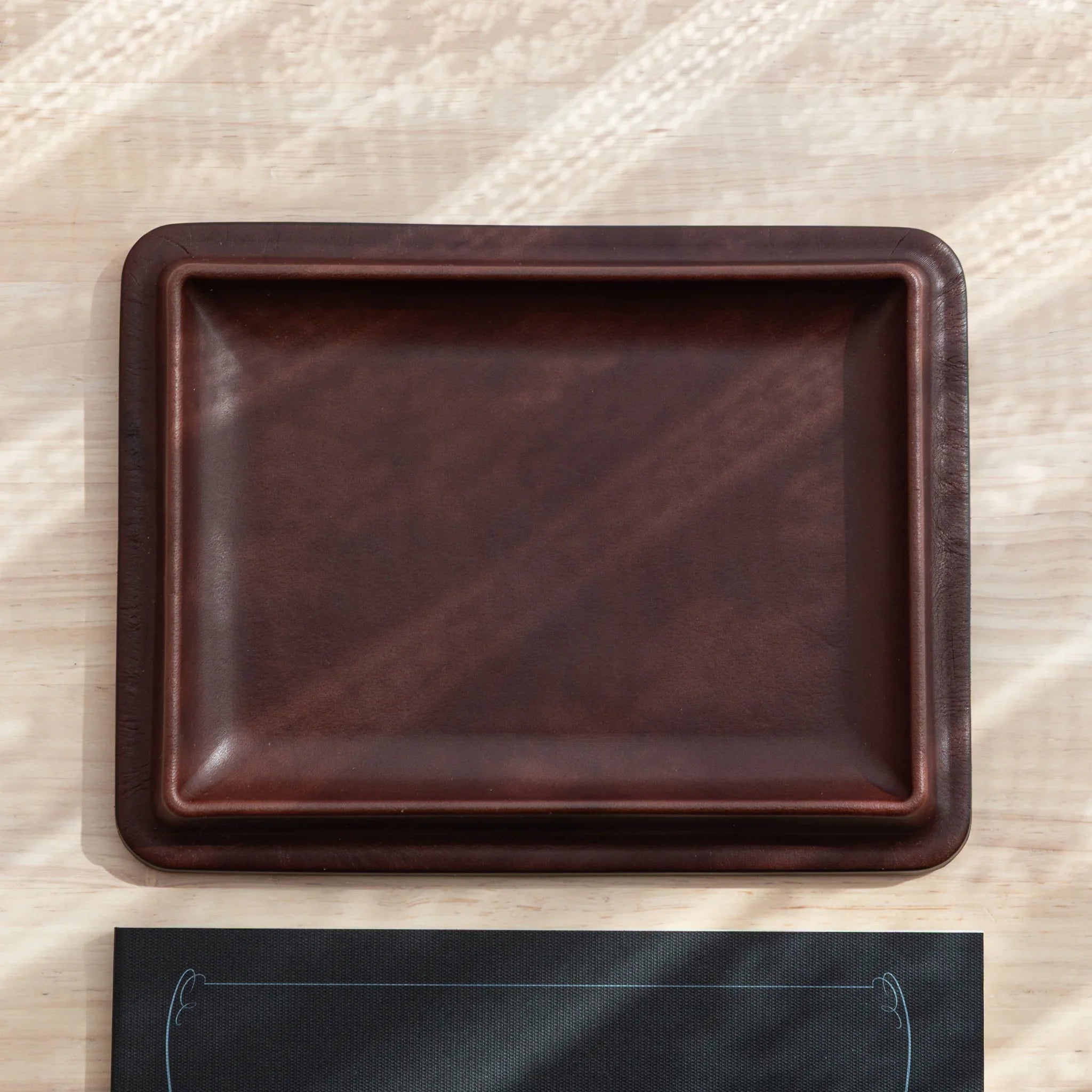 Japanese Pen Tray in tan leather shown empty on light wooden background.