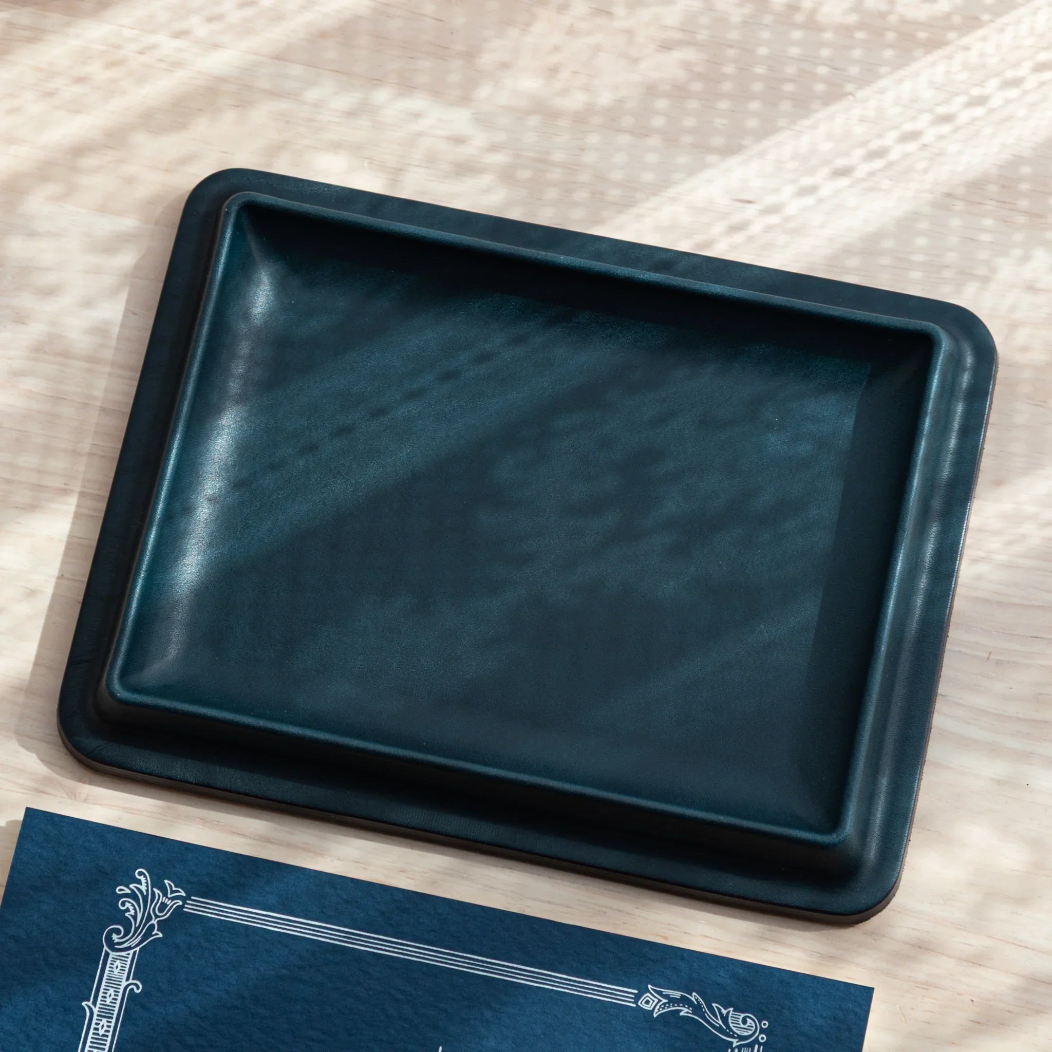 Teal wide leather pen tray photographed at angled perspective, showing contoured rectangular interior design and form