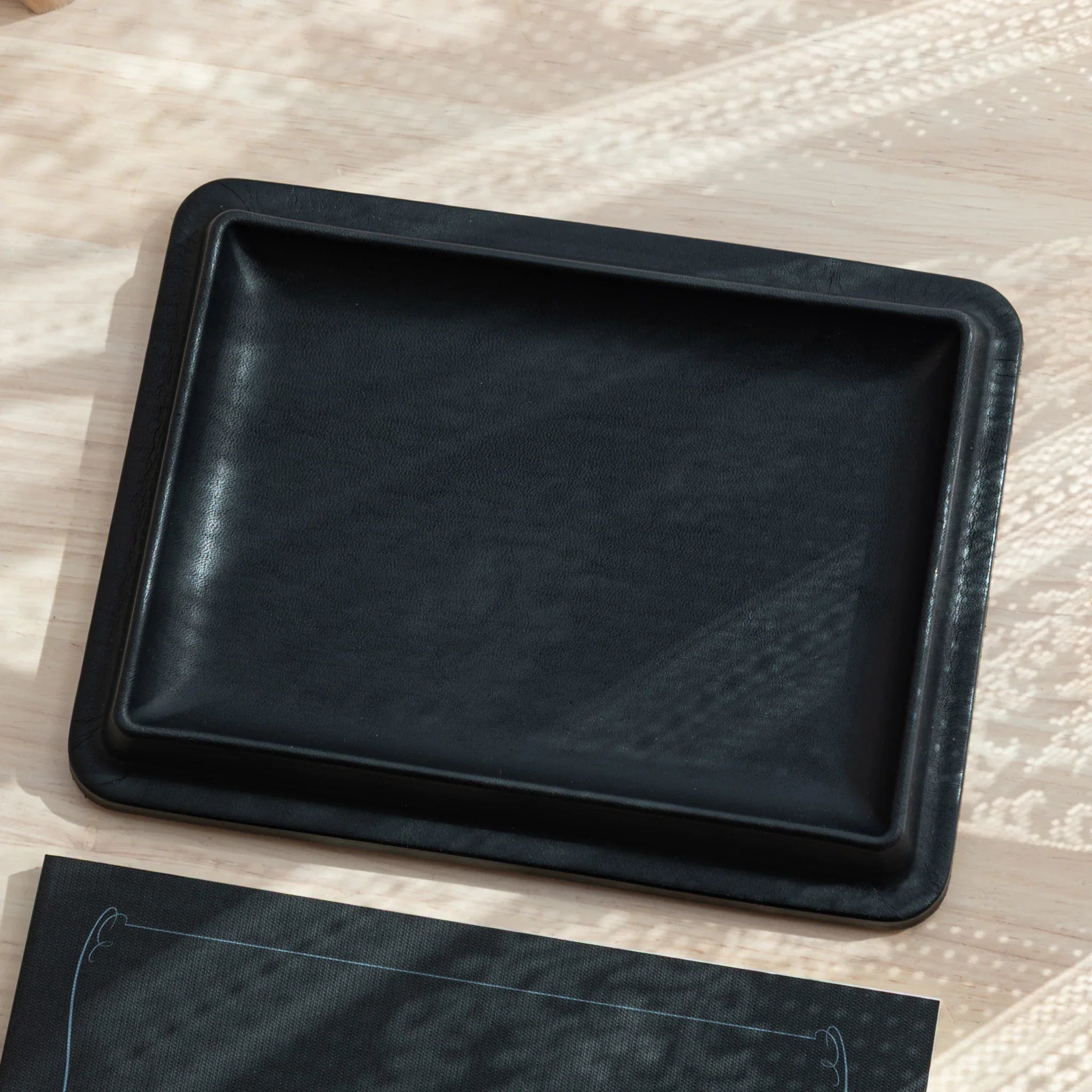 Angled view of black Japanese Pen Tray placed on a light wooden desk.