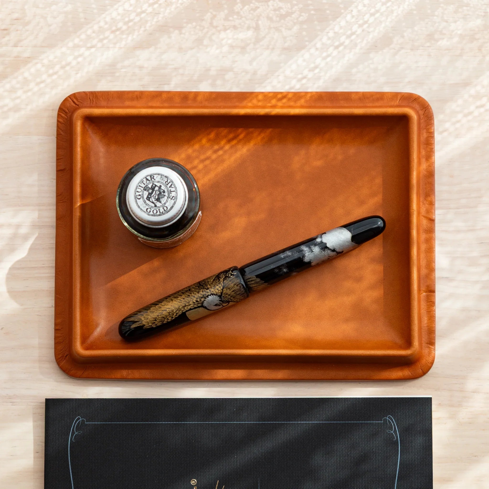 Japanese Pen Tray in deep camel leather, holding a ink bottle and a lacquered fountain pen.