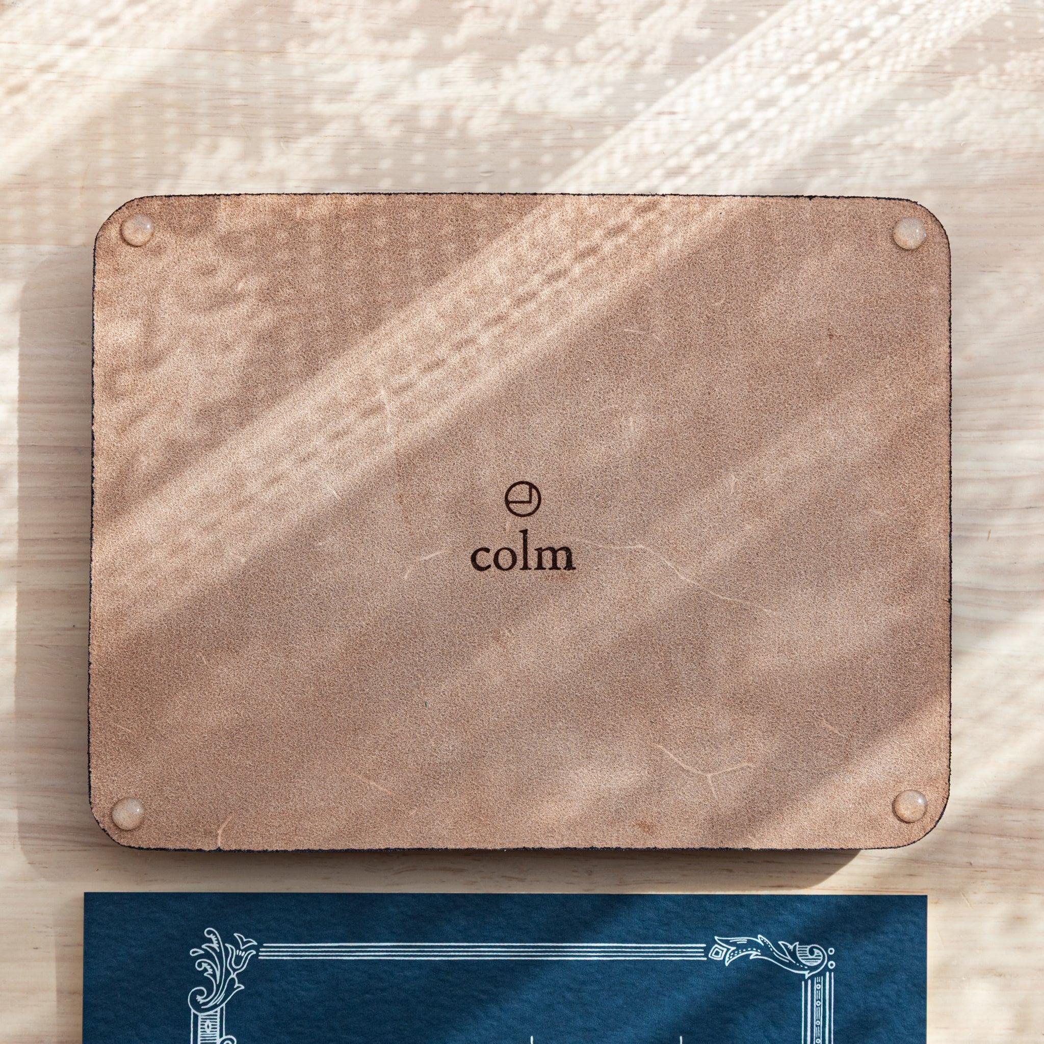 Tan wide leather pen tray viewed from directly above displaying multiple fountain pens arranged on suede surface