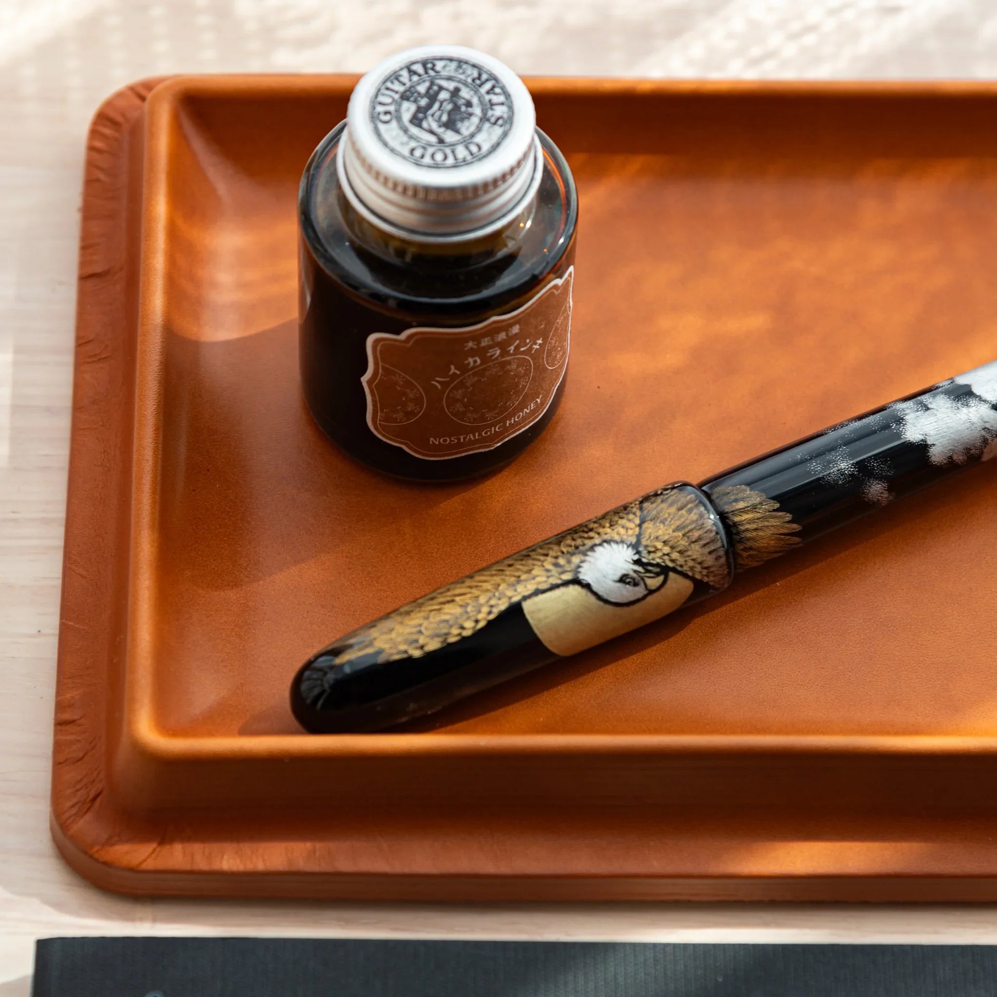Close-up of camel Japanese Pen Tray with ink and decorated Japanese fountain pen.