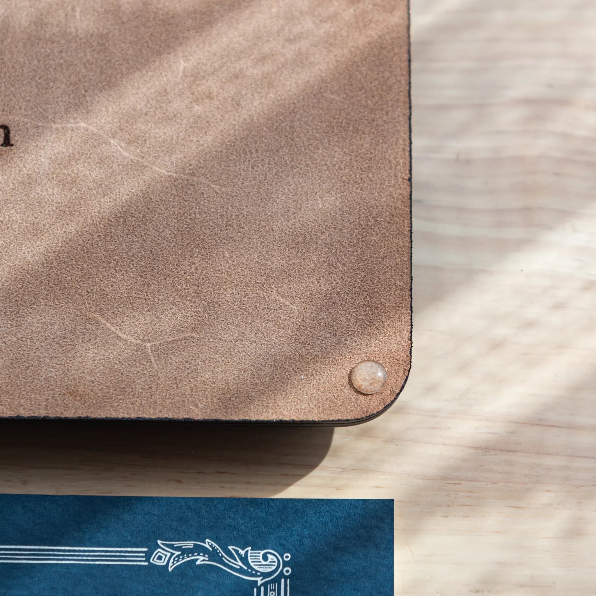 Tan wide leather pen tray rear view with exposed tan suede backing featuring embossed colm brand identification logo