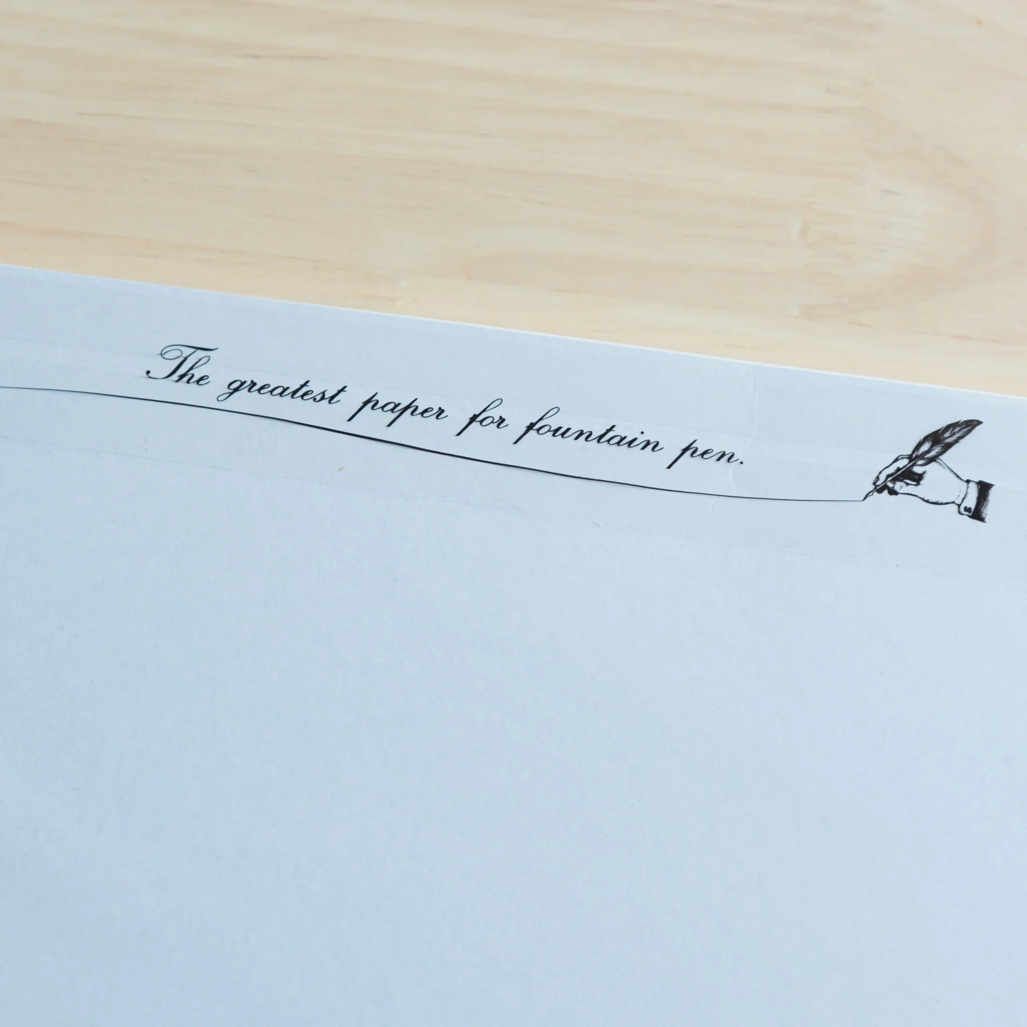 Sanzen Tomoe River FP fountain pen loose leaf paper flat lay on light wooden surface displaying pale blue high-quality sheets