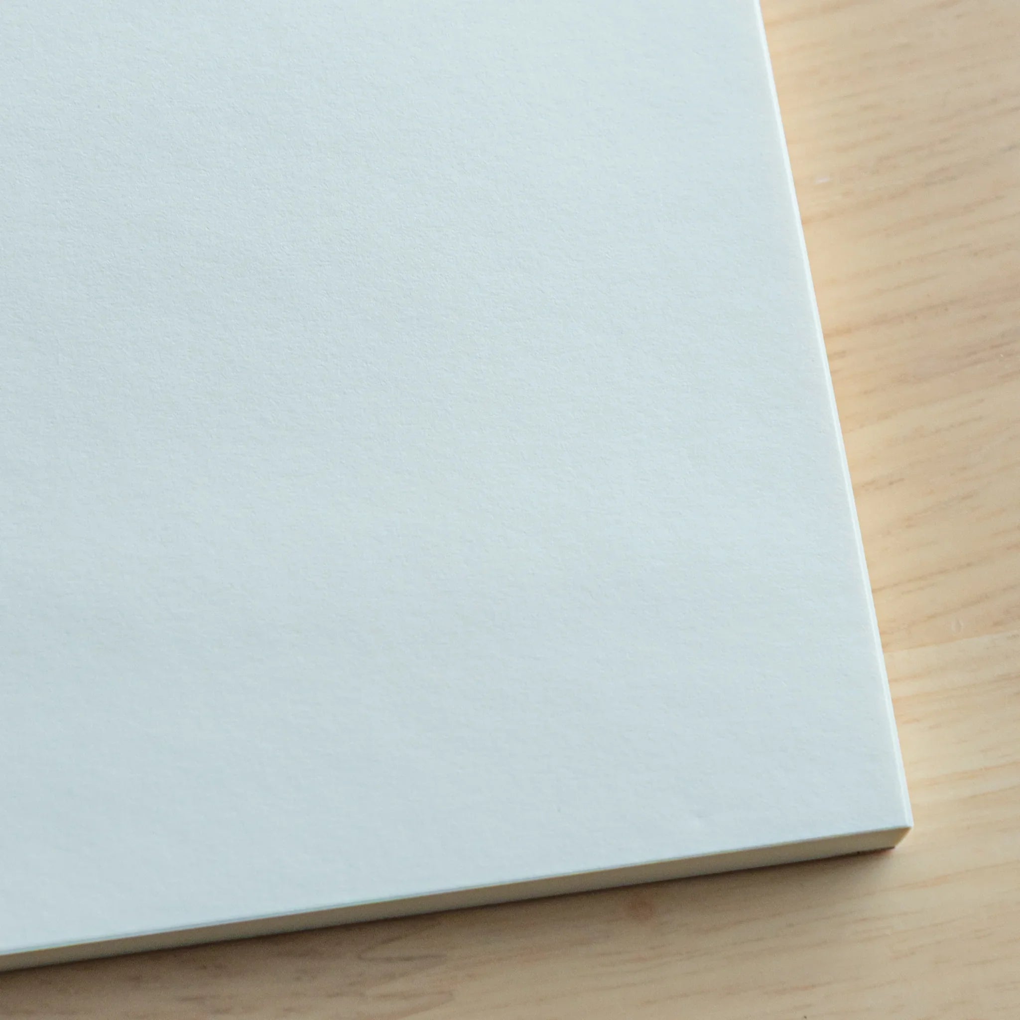 Single page shot at diagonal angle emphasizing page corner, binding thickness and paper weight quality