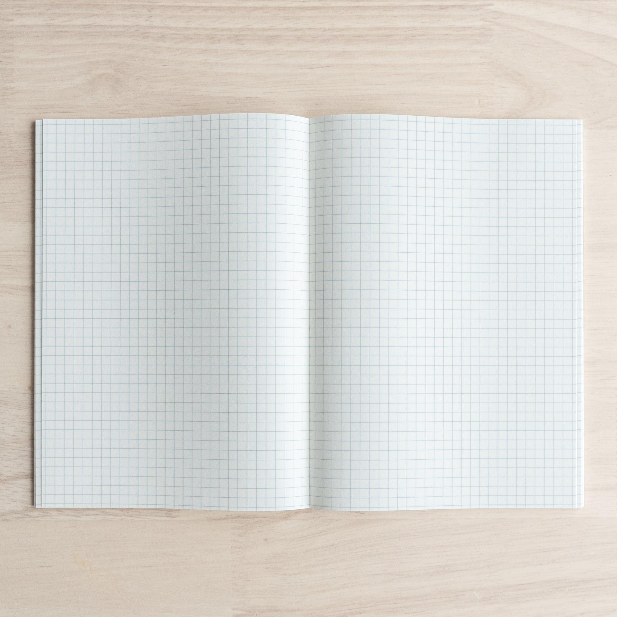 An open Tomoe River notebook displaying white pages with a 5mm grid pattern, ideal for precise writing or drawing.