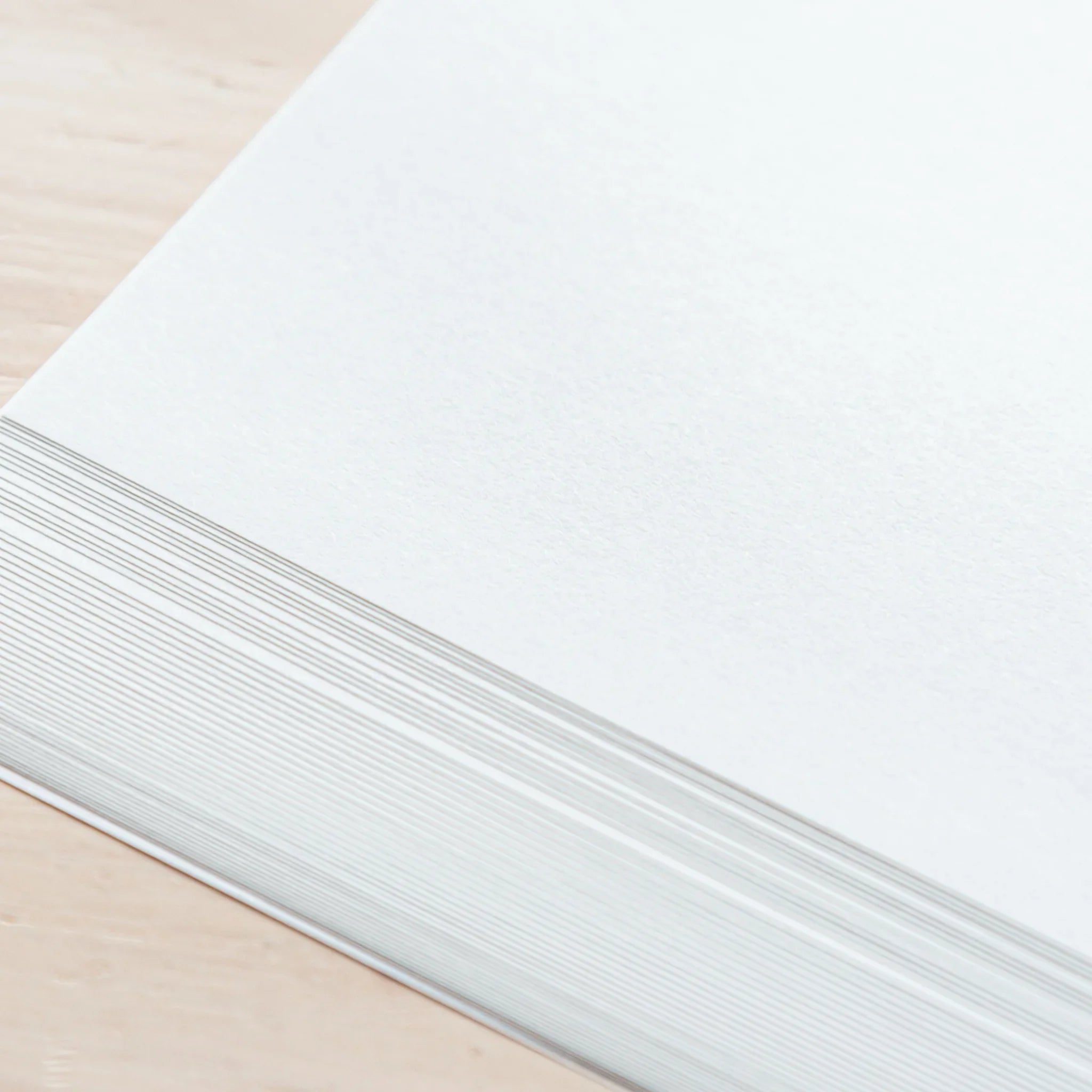 Close-up of Tomoegawa Tomoe River loose leaf paper in A4 size, stacked neatly with smooth edges on a desk.