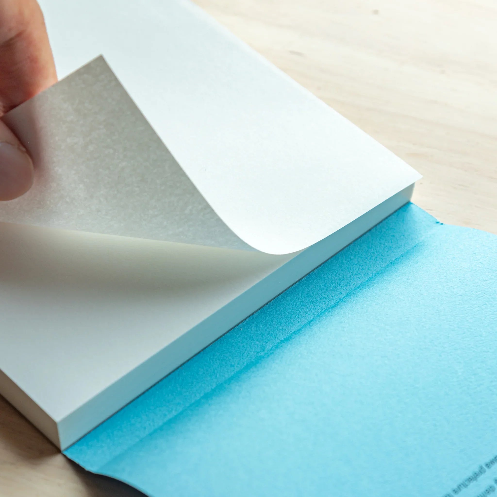 Hand peeling a sheet from the Tomoegawa Tomoe River A5 Writing Pad, showing how easily each page detaches from the pad.