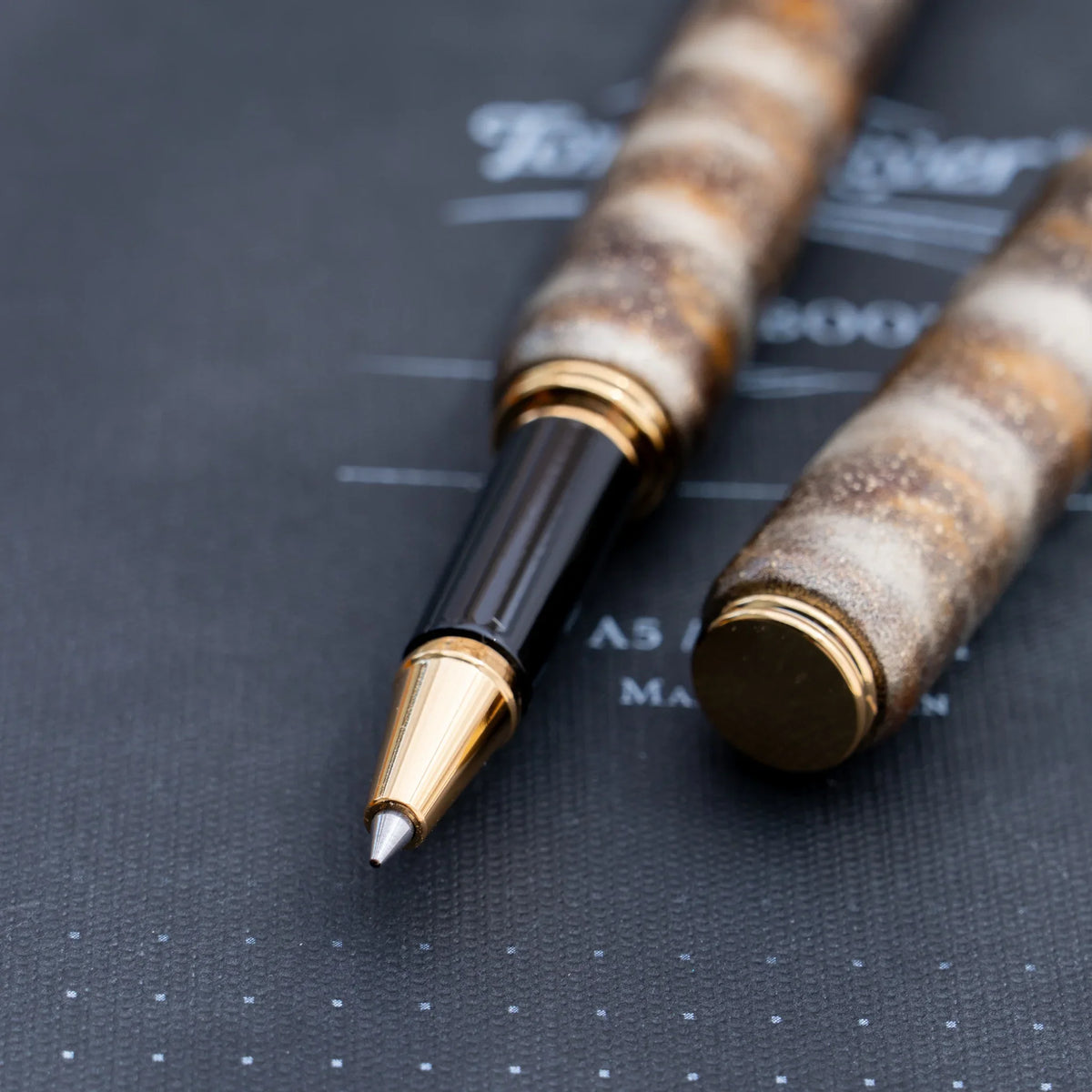 Gold trimmed rollerball tip of the translucent brown marbled urushi lacquered rollerball pen
