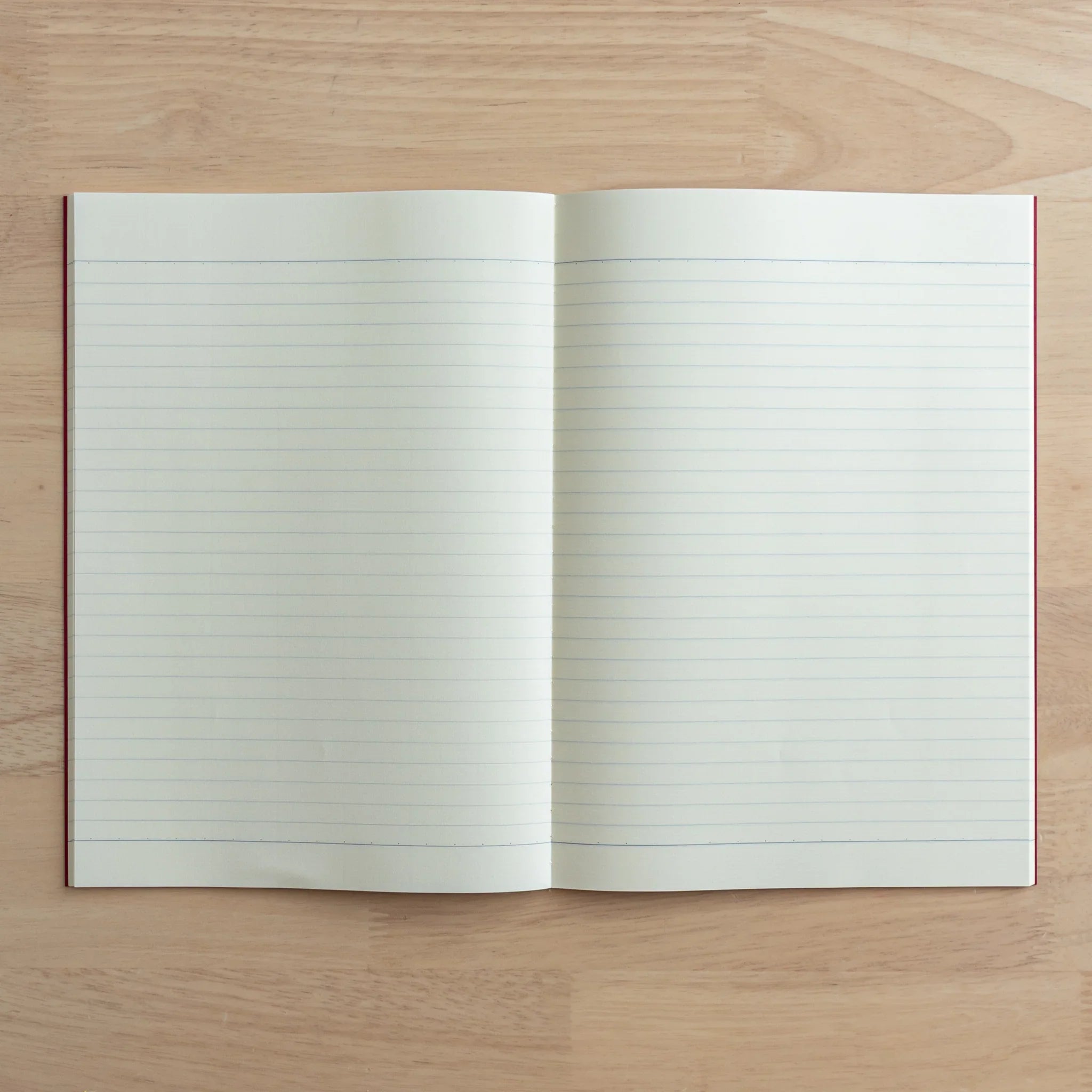 Tsubame Fools Cream Notebook open with grid pages visible, cream-colored paper with saddle-stitch binding detail