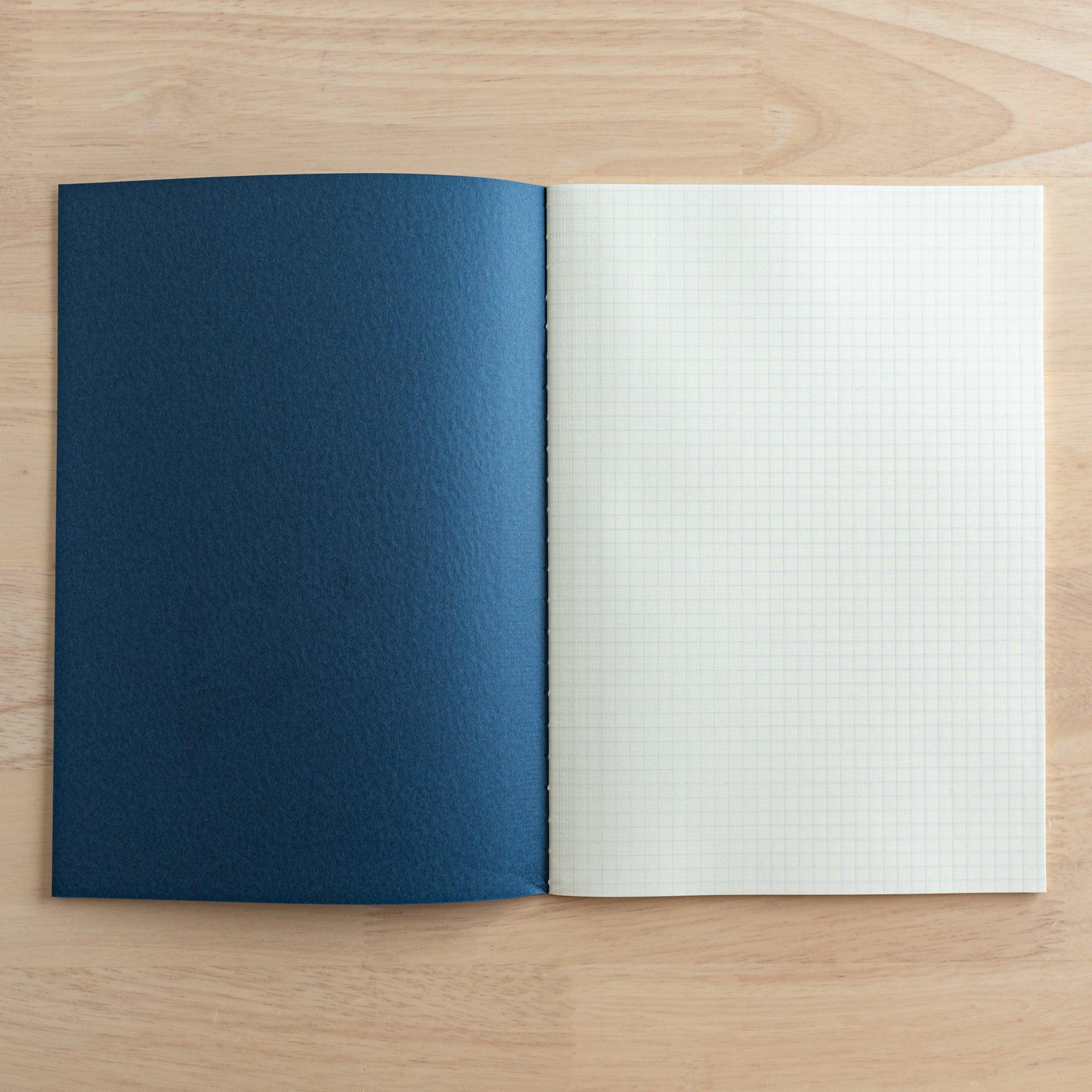 An open Tsubame Japanese notebook showing its navy blue cover and cream-colored grid paper, perfect for precise writing. A hallmark of Japanese stationery.
