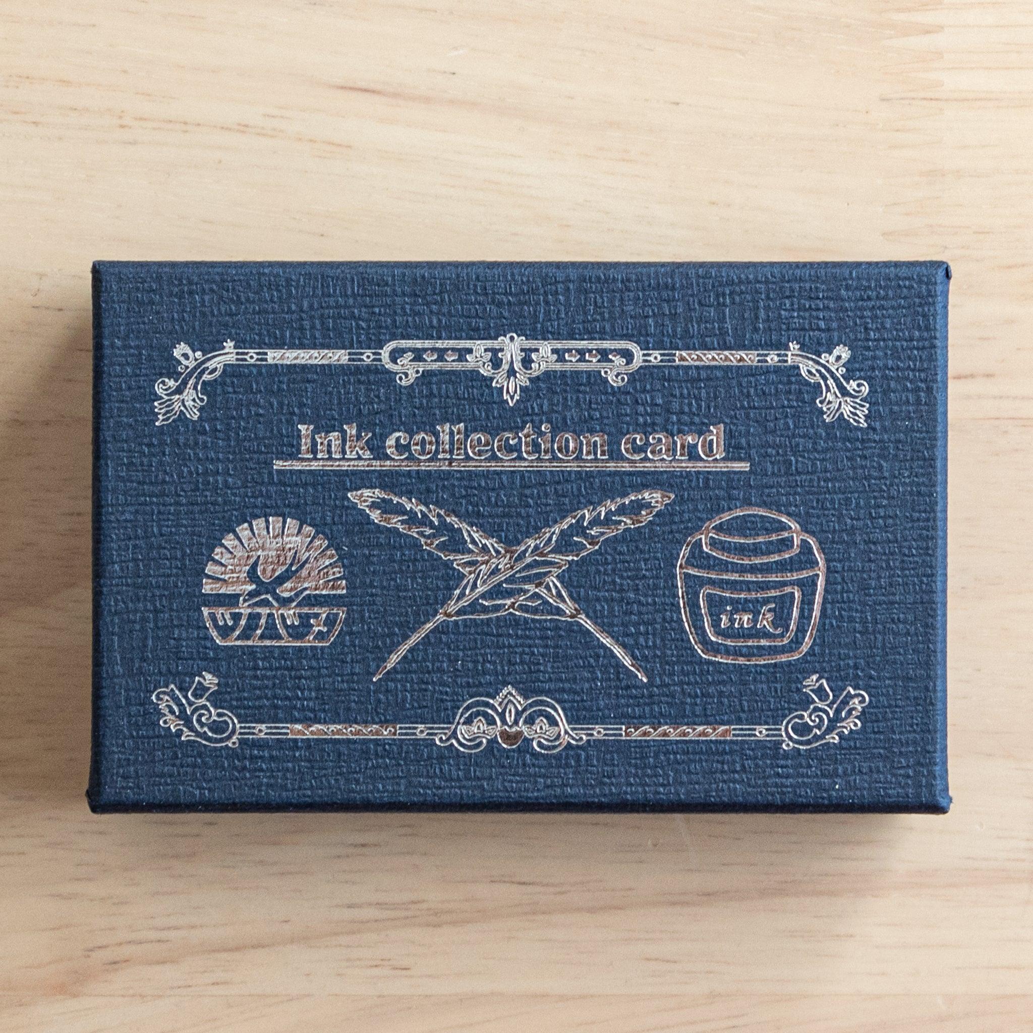 A navy Tsubame Japanese stationery box with gold embossed details, featuring quills, an ink bottle, and the brand logo, designed for organizing fountain pen ink swatches.