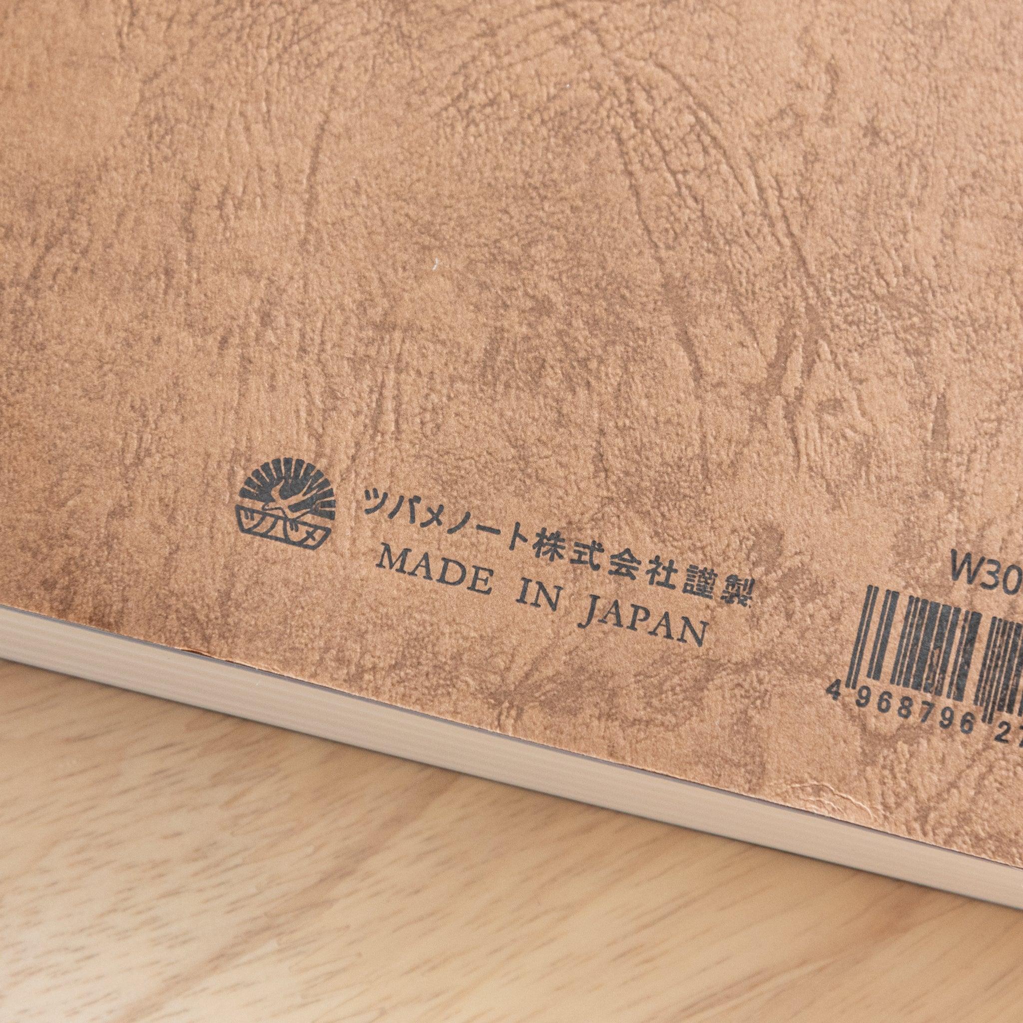 The back cover of a Japanese notebook with a textured brown design, featuring a barcode, brand logo, and "Made in Japan" text, showcasing fine Japanese stationery.