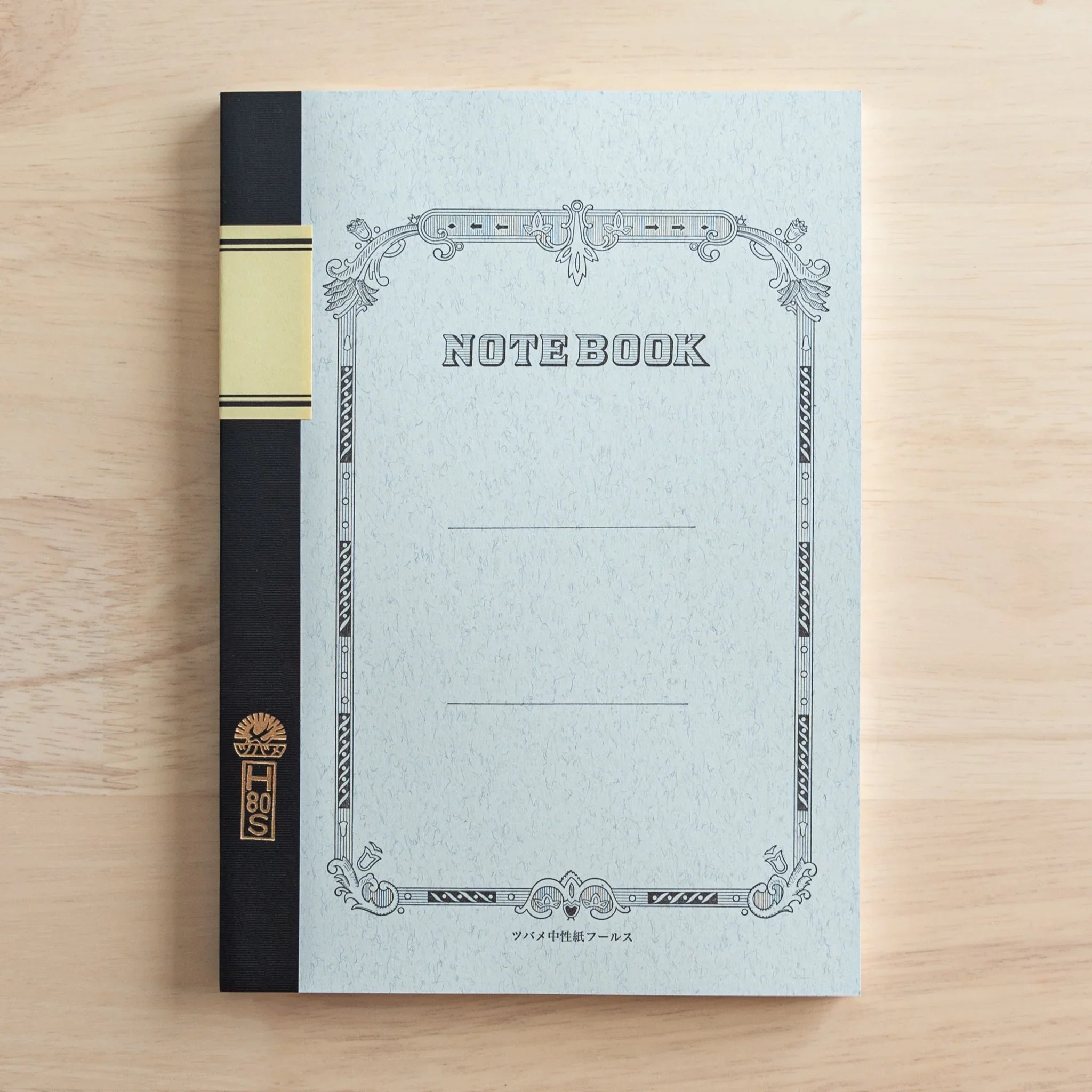 Angled front cover shot showing ornate decorative frame, cream paper stock and black fabric spine binding