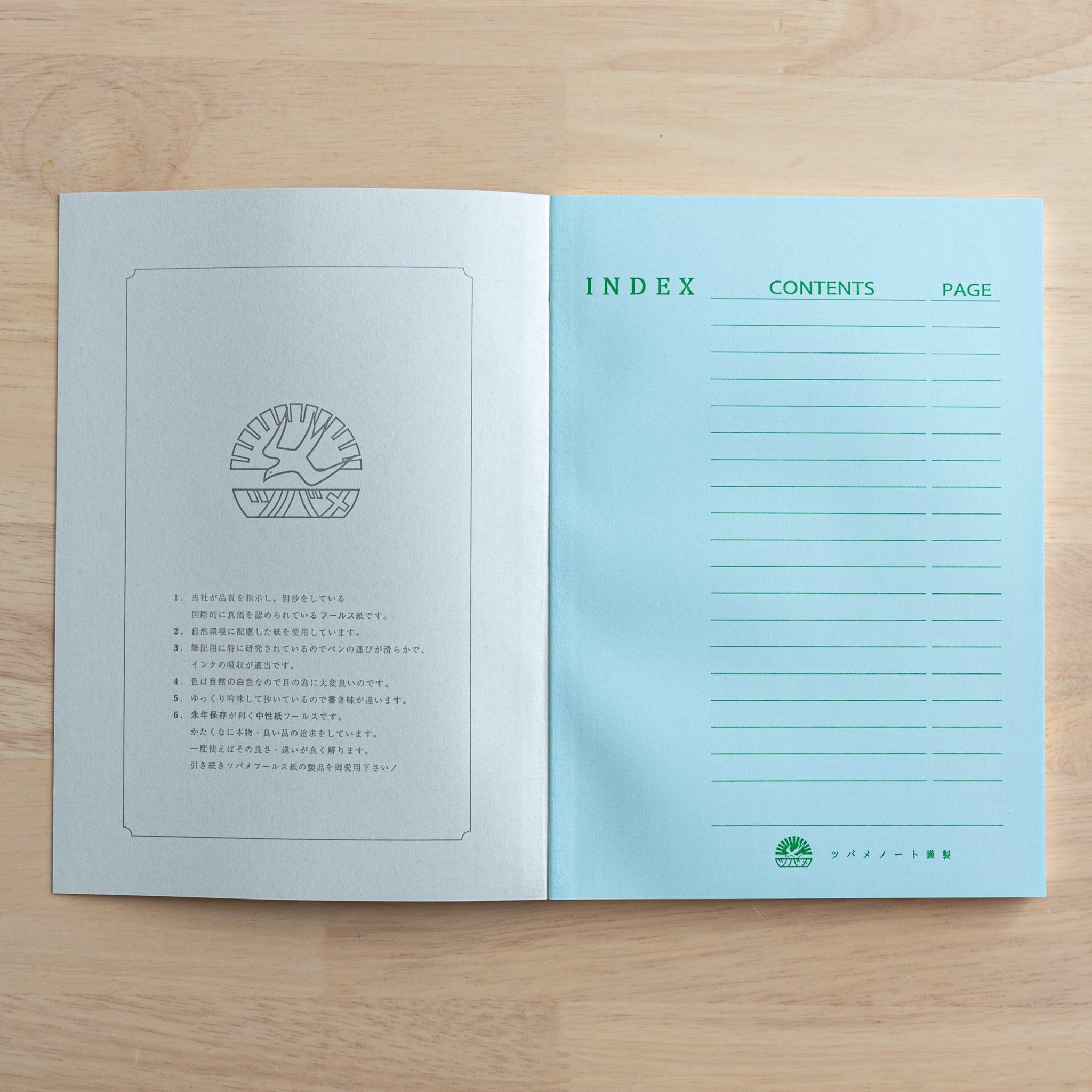 An open Tsubame Japanese notebook displaying a brand logo and product details on the left page and a blue index page with green text on the right, showcasing fine Japanese stationery.