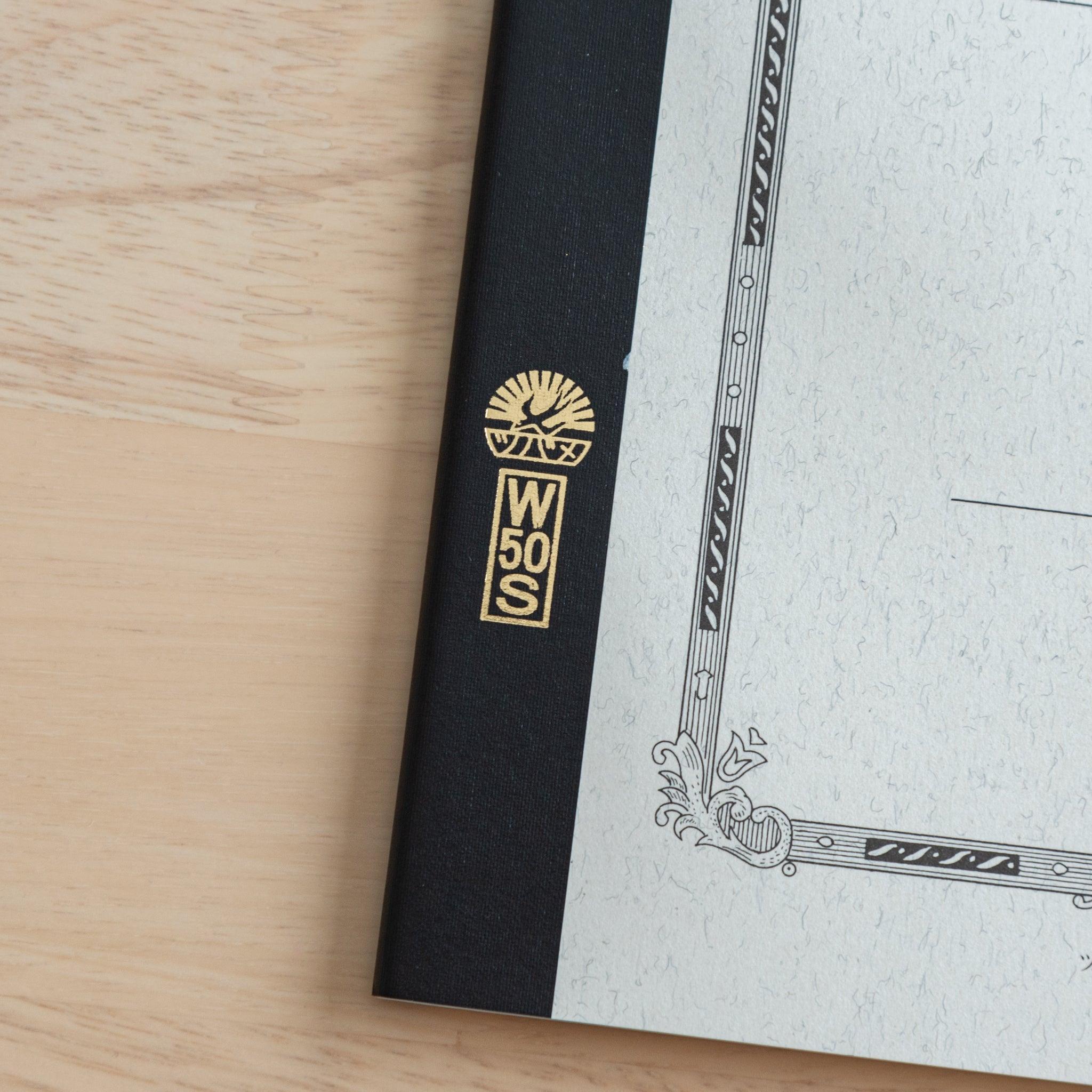 A close-up of the Tsubame Japanese notebook’s gold-stamped spine label, featuring the brand’s logo and model number, emphasizing fine Japanese stationery details.