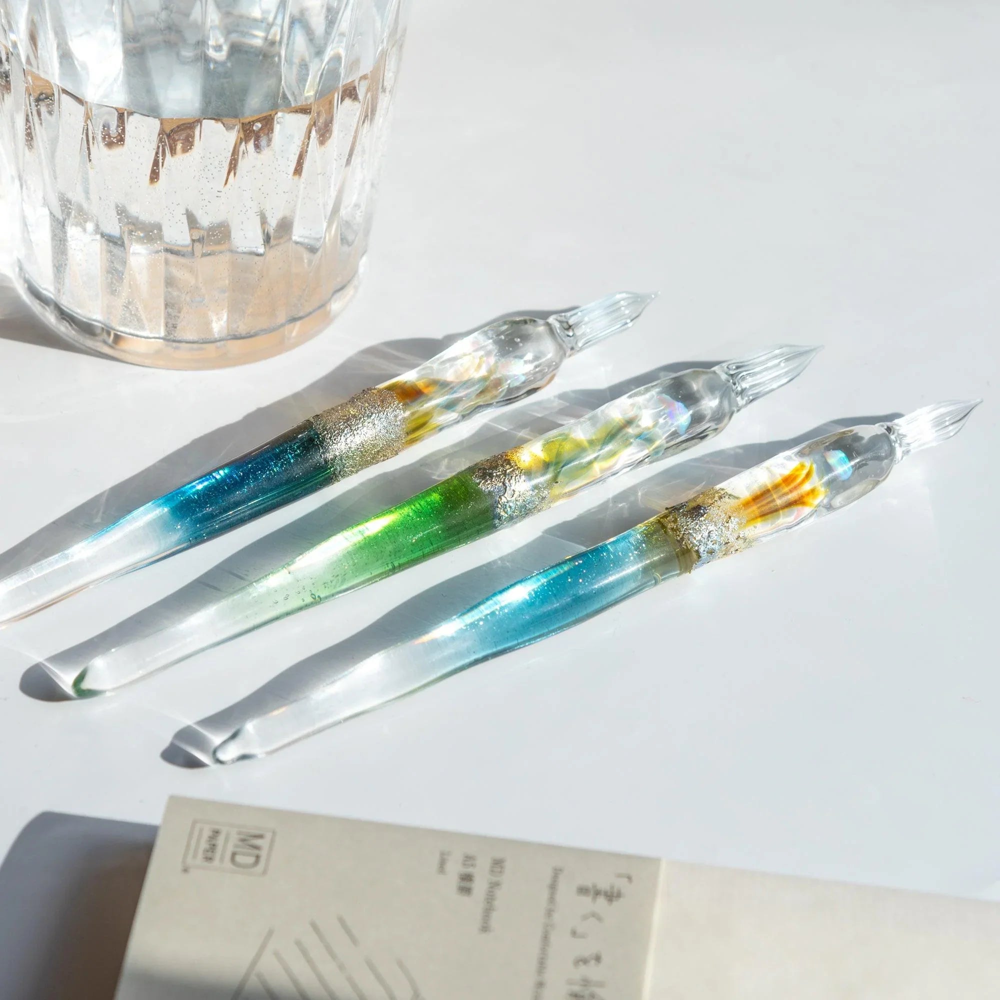 Side profile view of Tsukuyomi light blue glass dip pen with smooth barrel and twisted nib feature shine