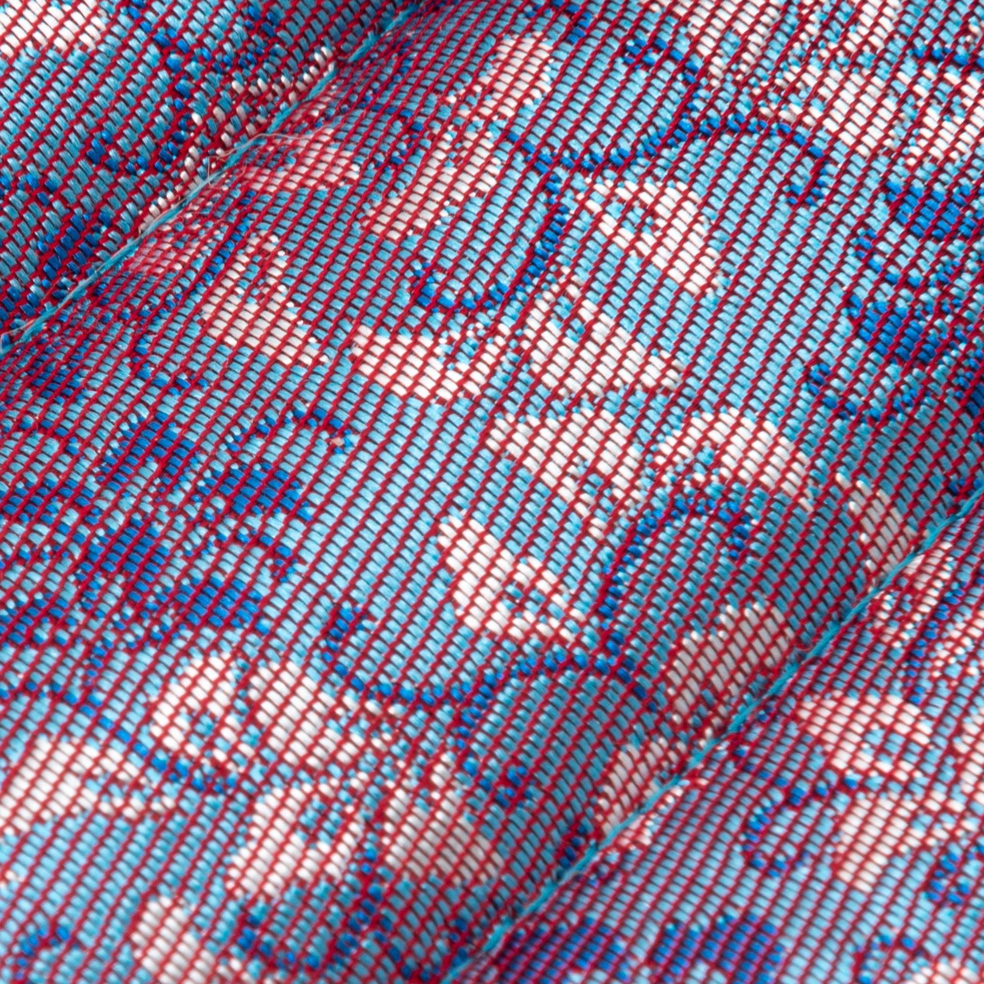 A detailed view of Nishijin silk fabric on a Japanese fountain pen case in pink and blue floral patterns, highlighting its intricate weave and vivid colors.