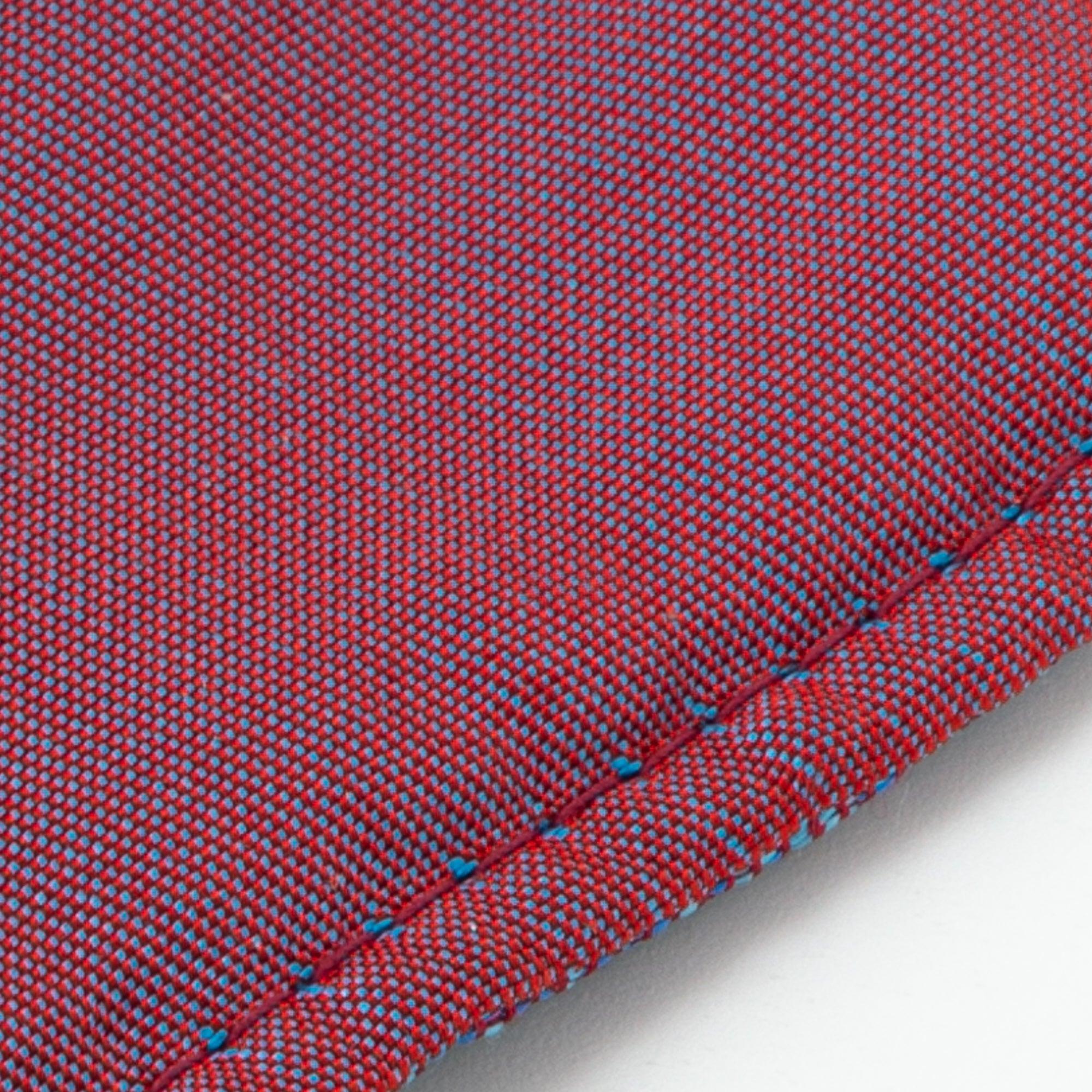 A close-up of the reverse side of Nishijin silk fabric on a Japanese fountain pen case, displaying fine red and blue threadwork and smooth stitching, made of 100% silk.
