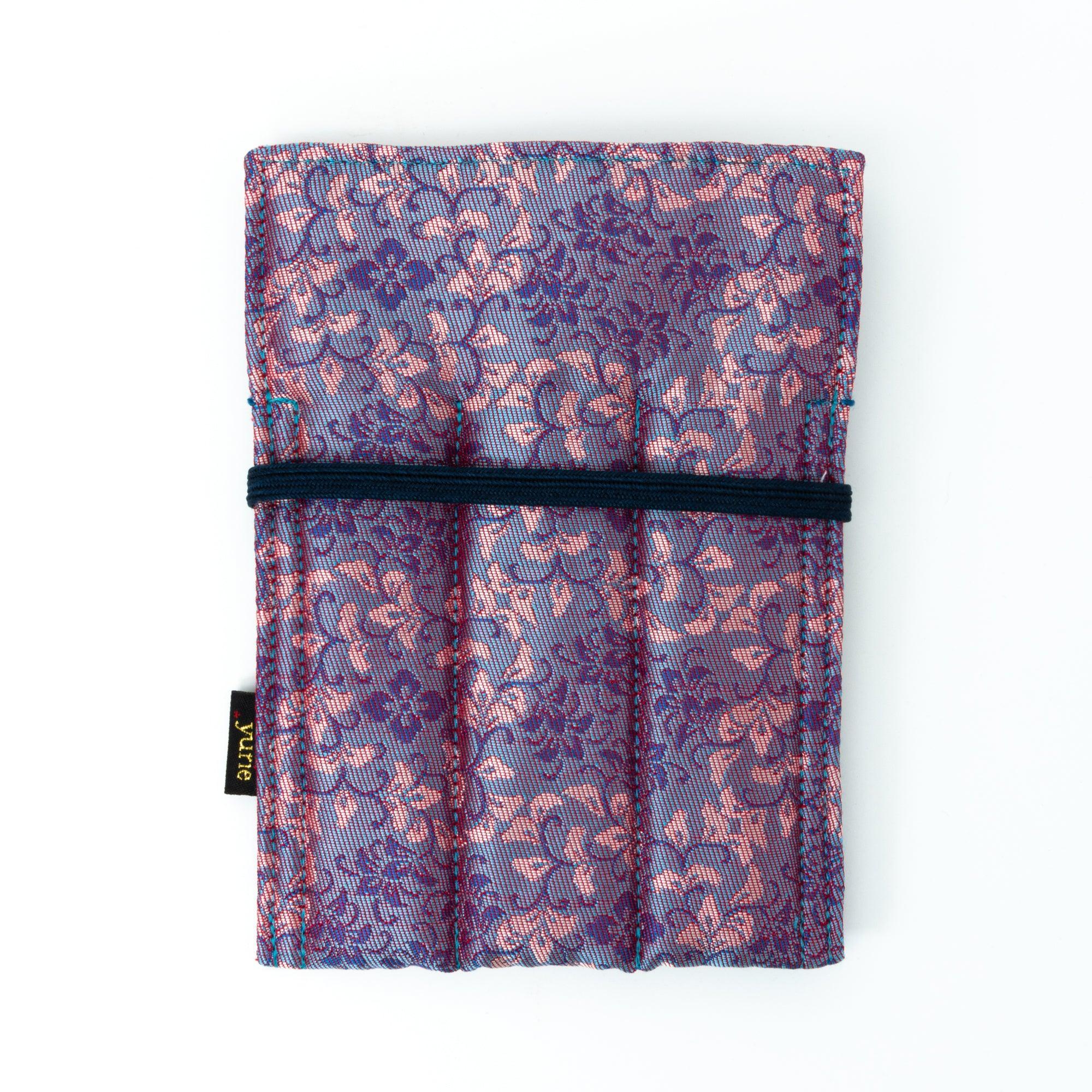 A Japanese fountain pen case in Nishijin silk with pink and blue floral patterns, featuring a navy cord and red bead, displayed flat against a white background.